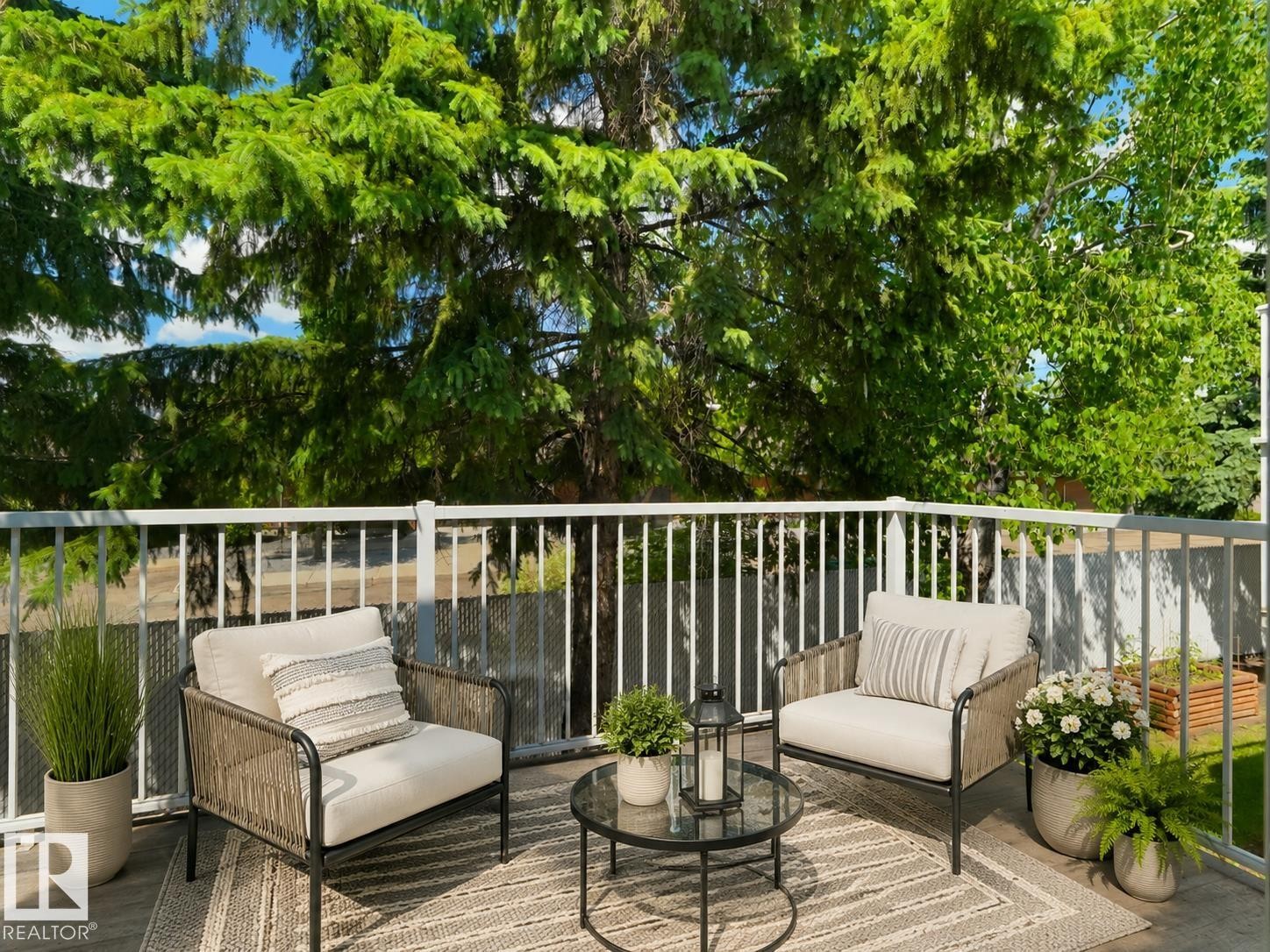 Private outdoor balcony featuring a white railing, a dark grey composite deck, and mature trees - 1855 Mill Woods Rd E Nw, Edmonton, AB
