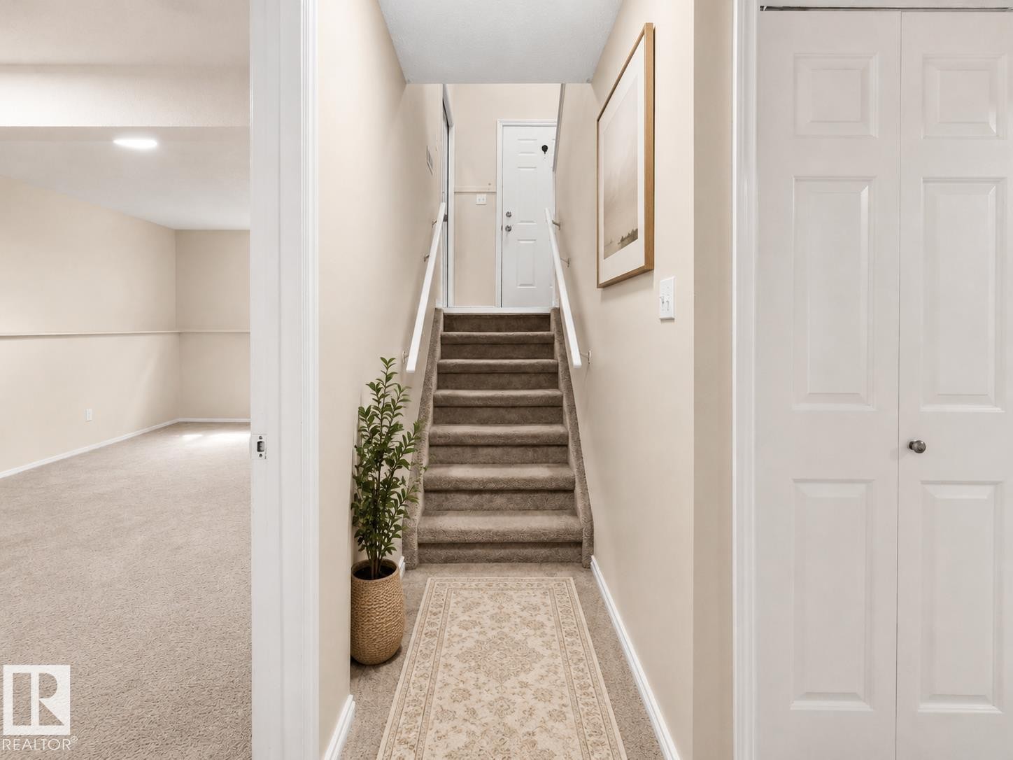 Carpeted staircase with white handrails leading to a solid white door - 1855 Mill Woods Rd E Nw, Edmonton, AB