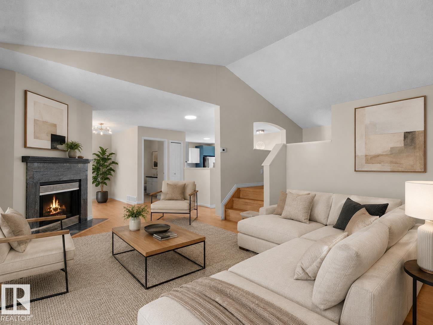 Spacious living area featuring a dark stone fireplace with a metal insert, light wood-finish flooring, and a vaulted ceiling - 1855 Mill Woods Rd E Nw, Edmonton, AB