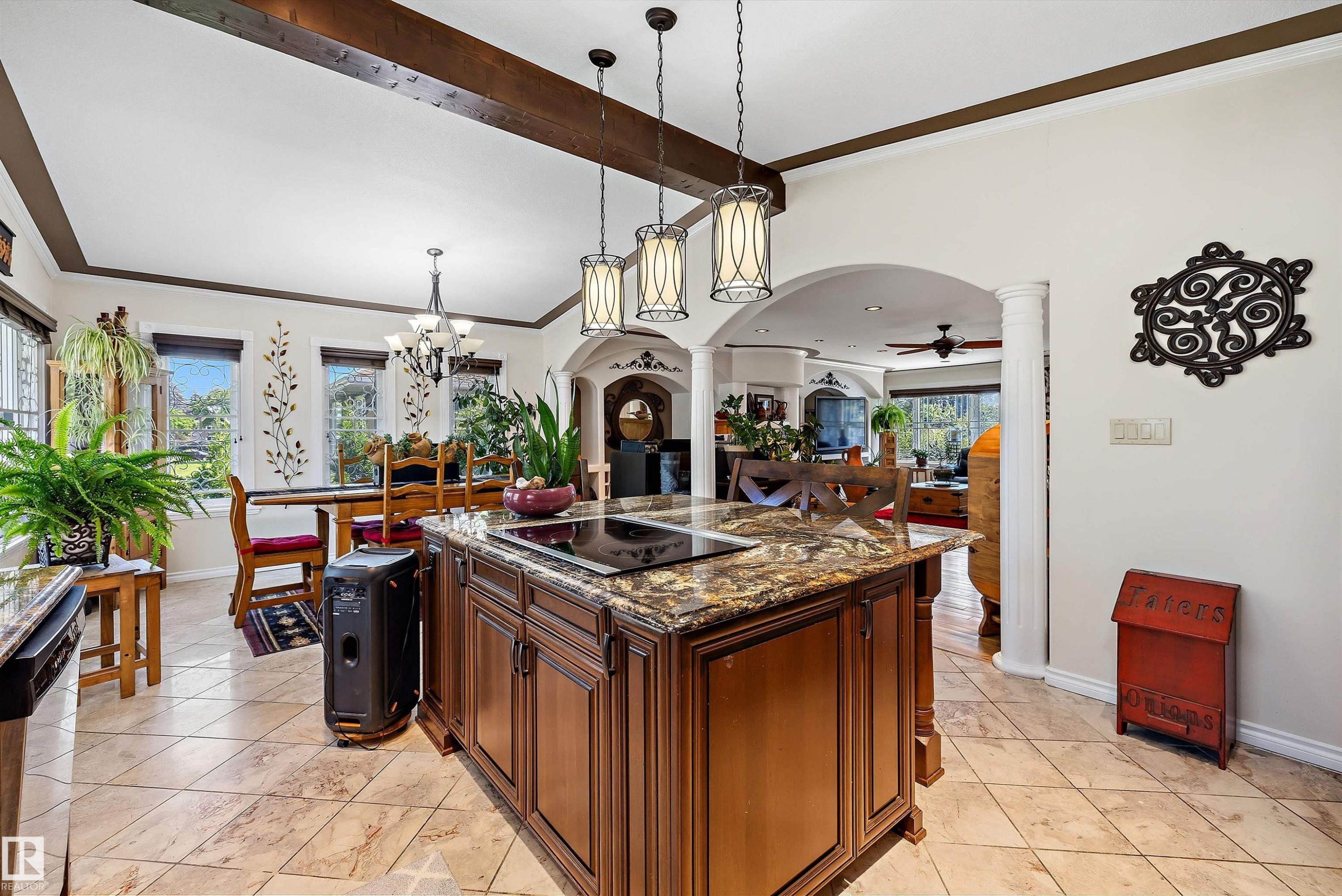 Central kitchen island with an integrated cooktop, granite-finish countertop, and rich wood-finish cabinetry - 11124 110A Avenue Nw, Edmonton, AB