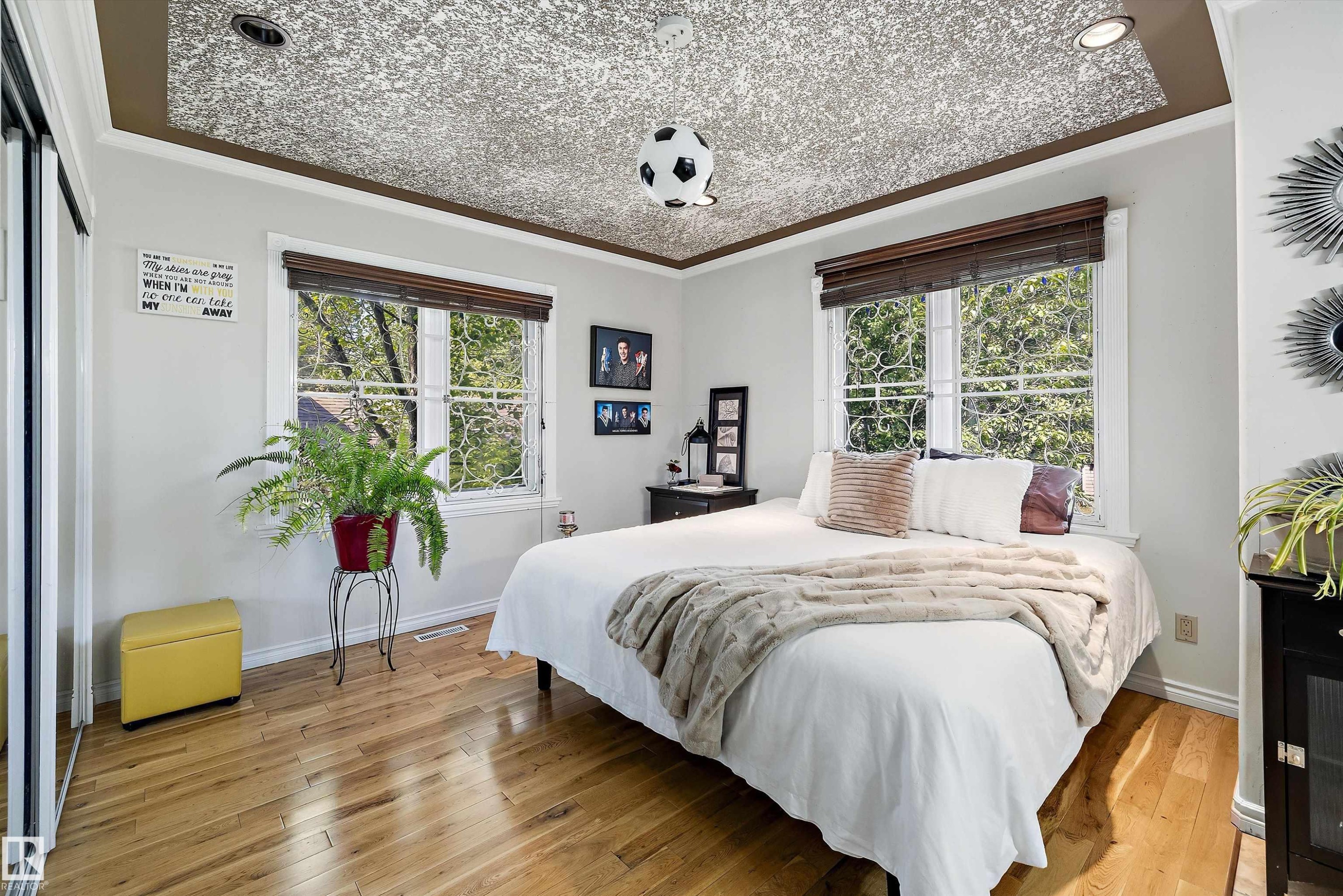 Hardwood flooring throughout featuring two windows with decorative grilles, white trim, and brown blinds - 11124 110A Avenue Nw, Edmonton, AB