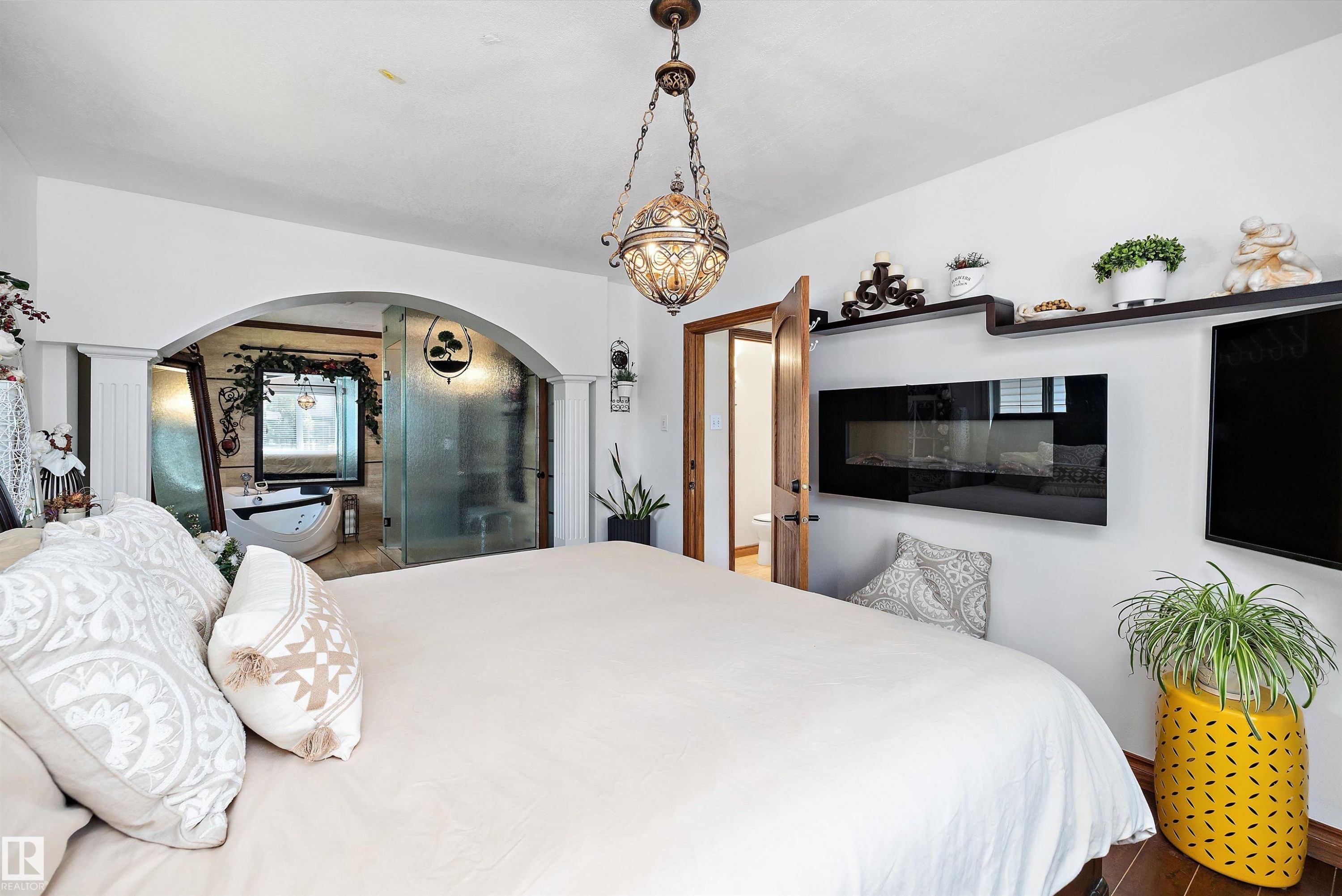 Bedroom with dark wood-finish flooring, a contemporary wall-mounted fireplace, and built-in shelving - 11124 110A Avenue Nw, Edmonton, AB