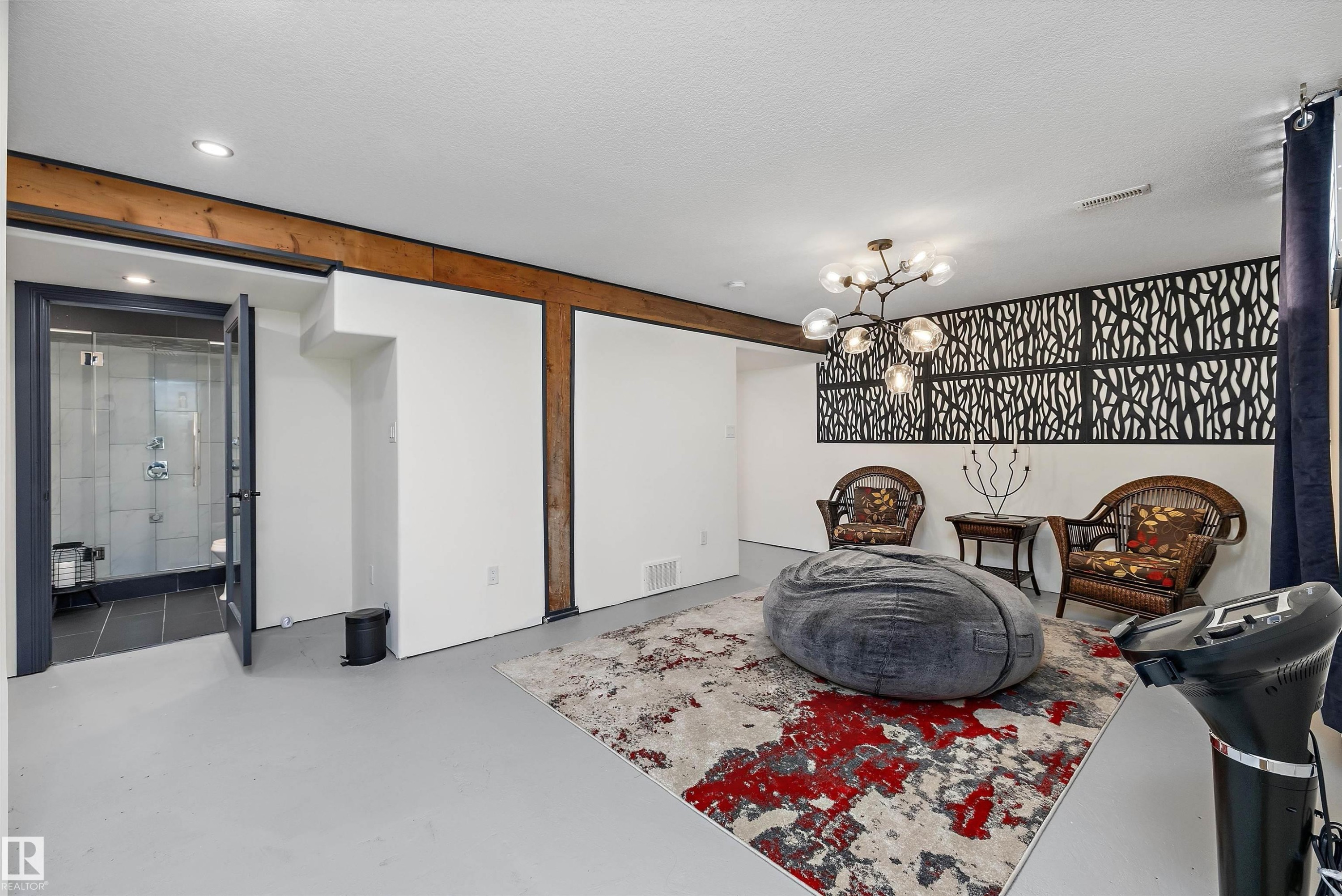 Open concept lower level featuring light gray flooring, exposed timber beams, a decorative wall panel, and recessed lighting - 11124 110A Avenue Nw, Edmonton, AB