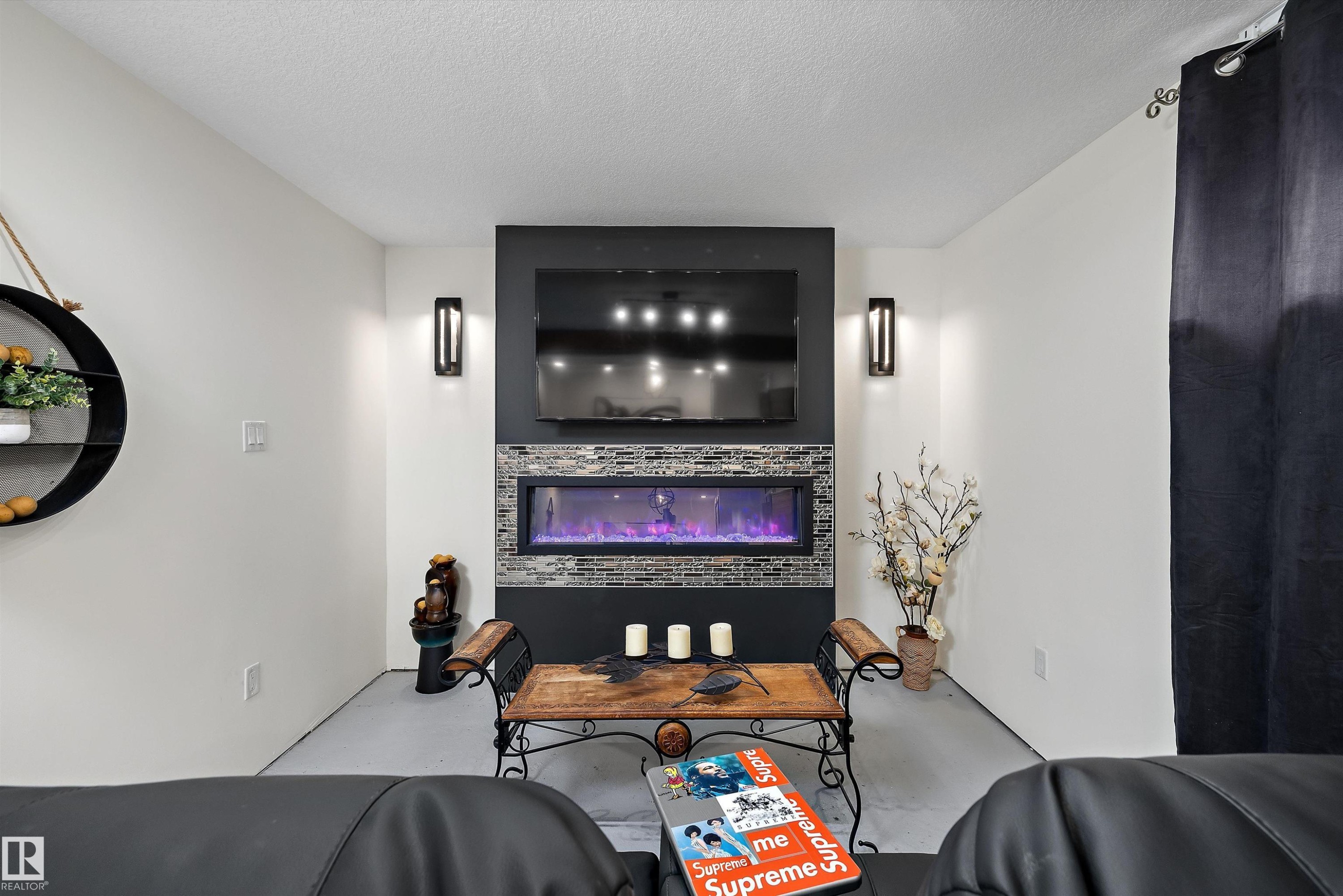 Integrated linear electric fireplace with stone-tile surround and wall-mounted television - 11124 110A Avenue Nw, Edmonton, AB