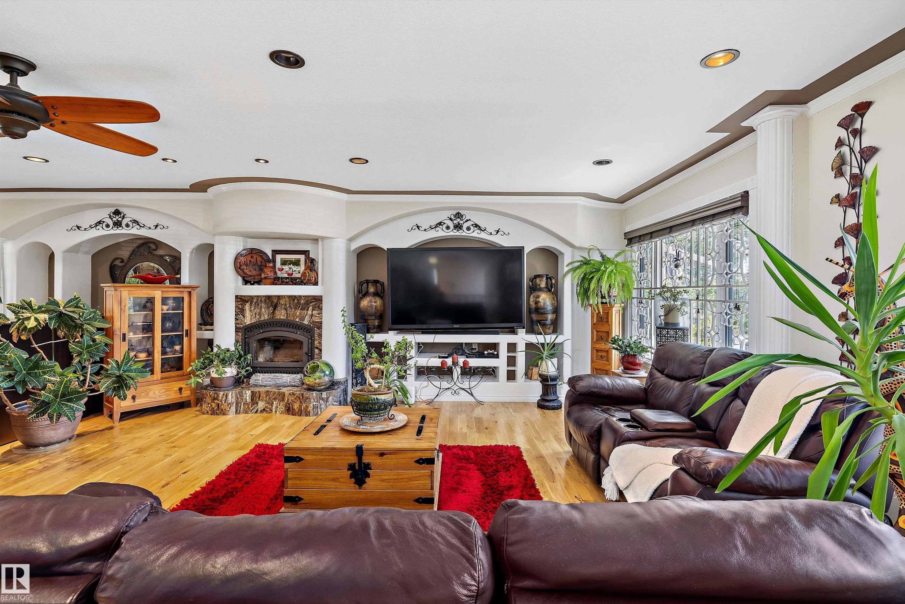 Spacious living area featuring wood-finish flooring, a built-in fireplace with a stone surround, and an integrated entertainment center - 11124 110A Avenue Nw, Edmonton, AB