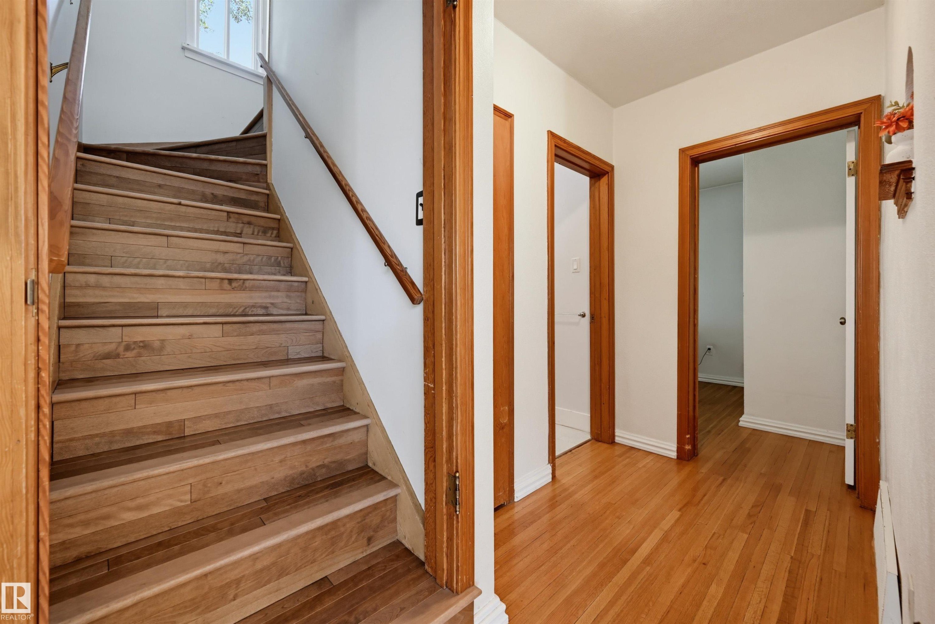 Hardwood staircase featuring a wood railing and white risers - 11619 122 Street, Edmonton, AB