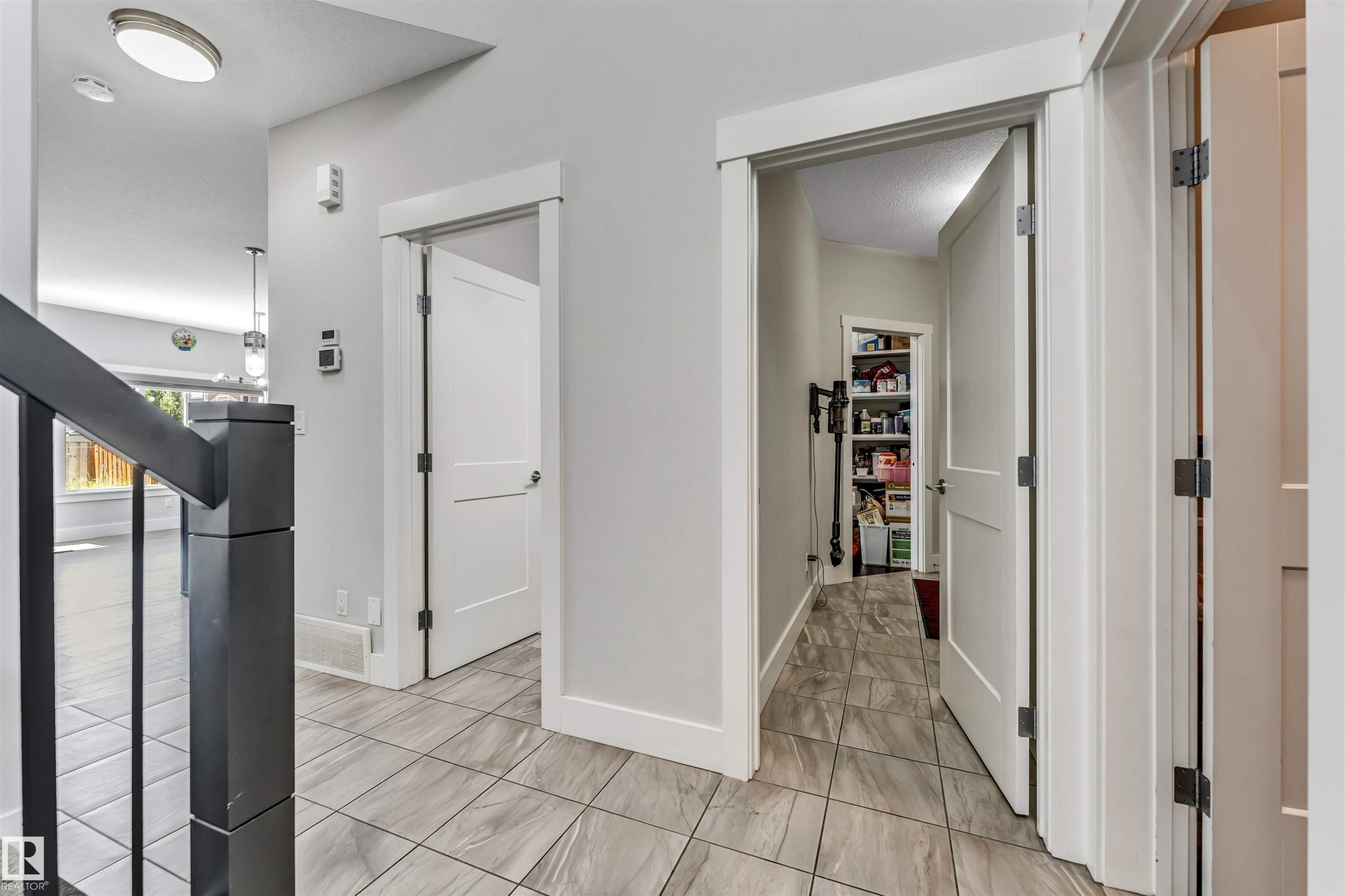Hallway featuring light gray walls and patterned tile flooring - 8516 216 Street, Edmonton, AB