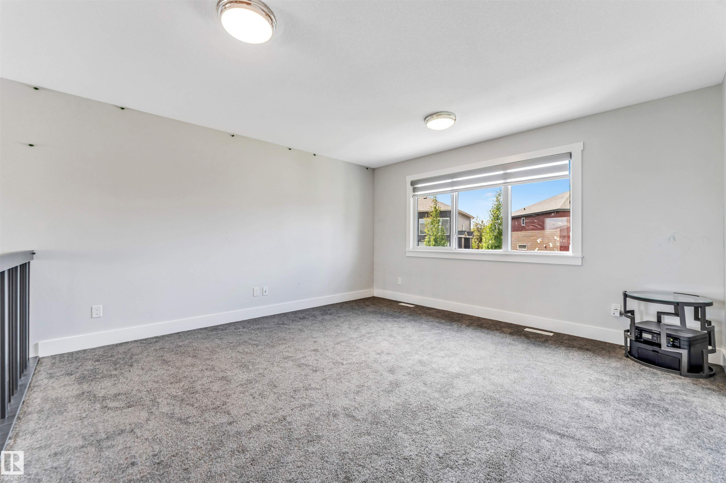 Spacious open-concept room featuring neutral gray walls and gray carpeting - 8516 216 Street, Edmonton, AB