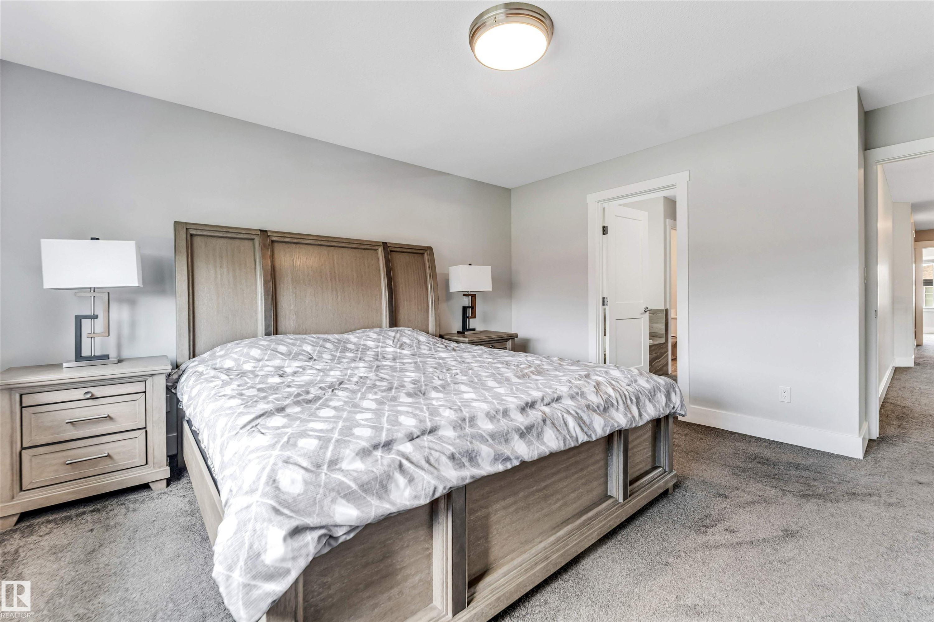 Spacious bedroom featuring light gray walls, plush gray carpeting, and white baseboards - 8516 216 Street, Edmonton, AB