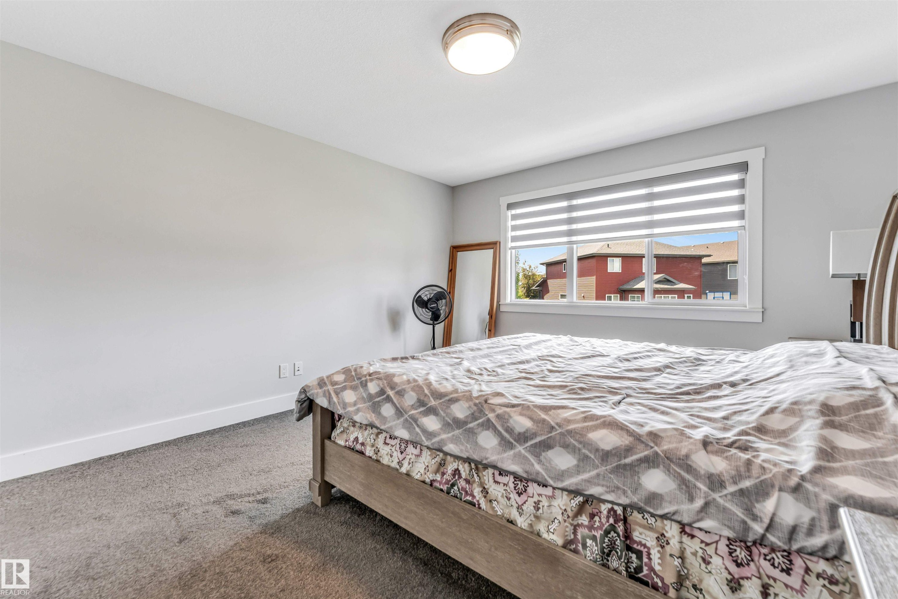 Carpeted room featuring light gray walls, a window with horizontal blinds, white trim, and a flush-mount ceiling light - 8516 216 Street, Edmonton, AB