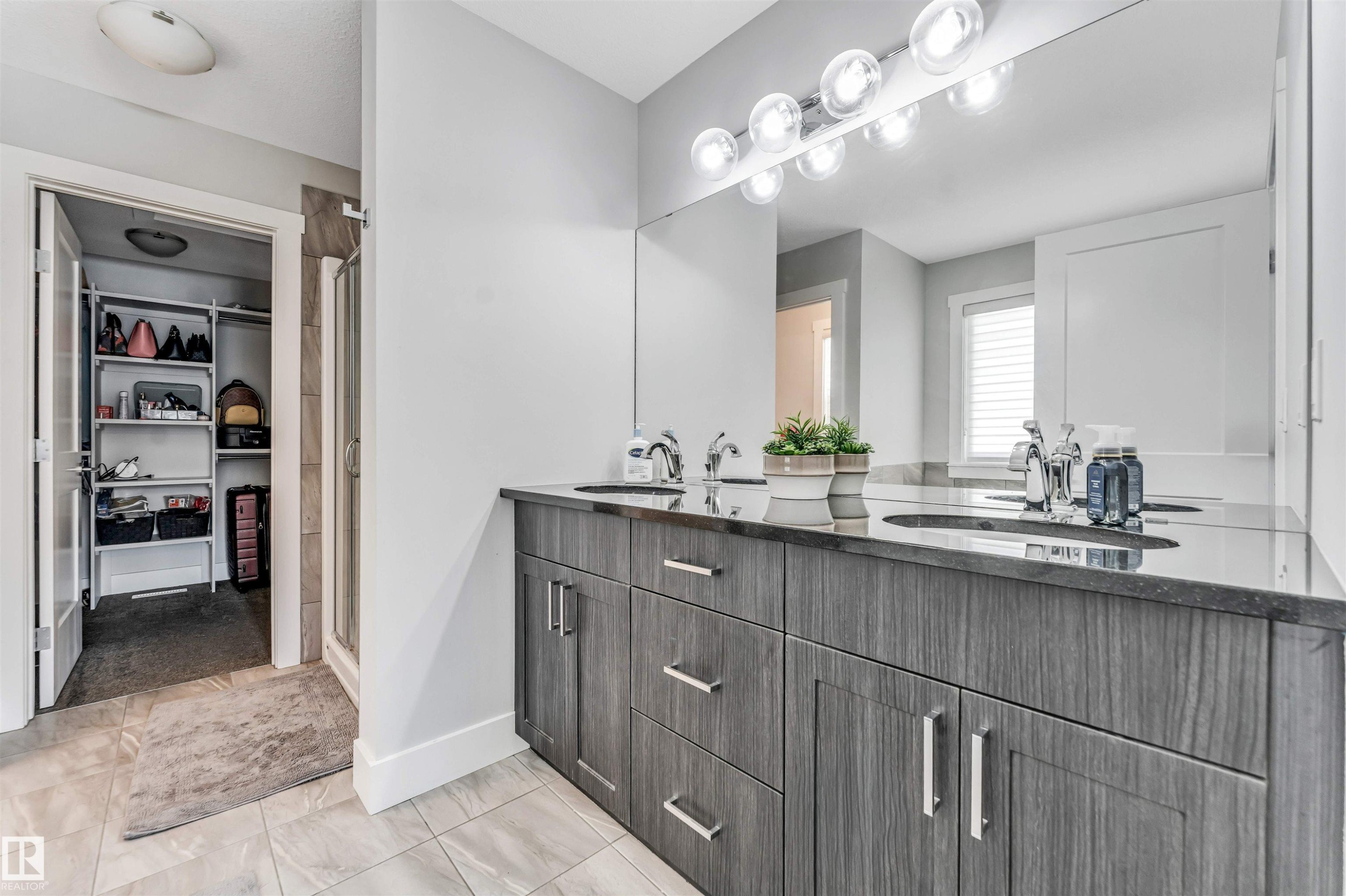 Bathroom featuring a double vanity with stone countertops, integrated sinks, and wood-finish cabinetry - 8516 216 Street, Edmonton, AB