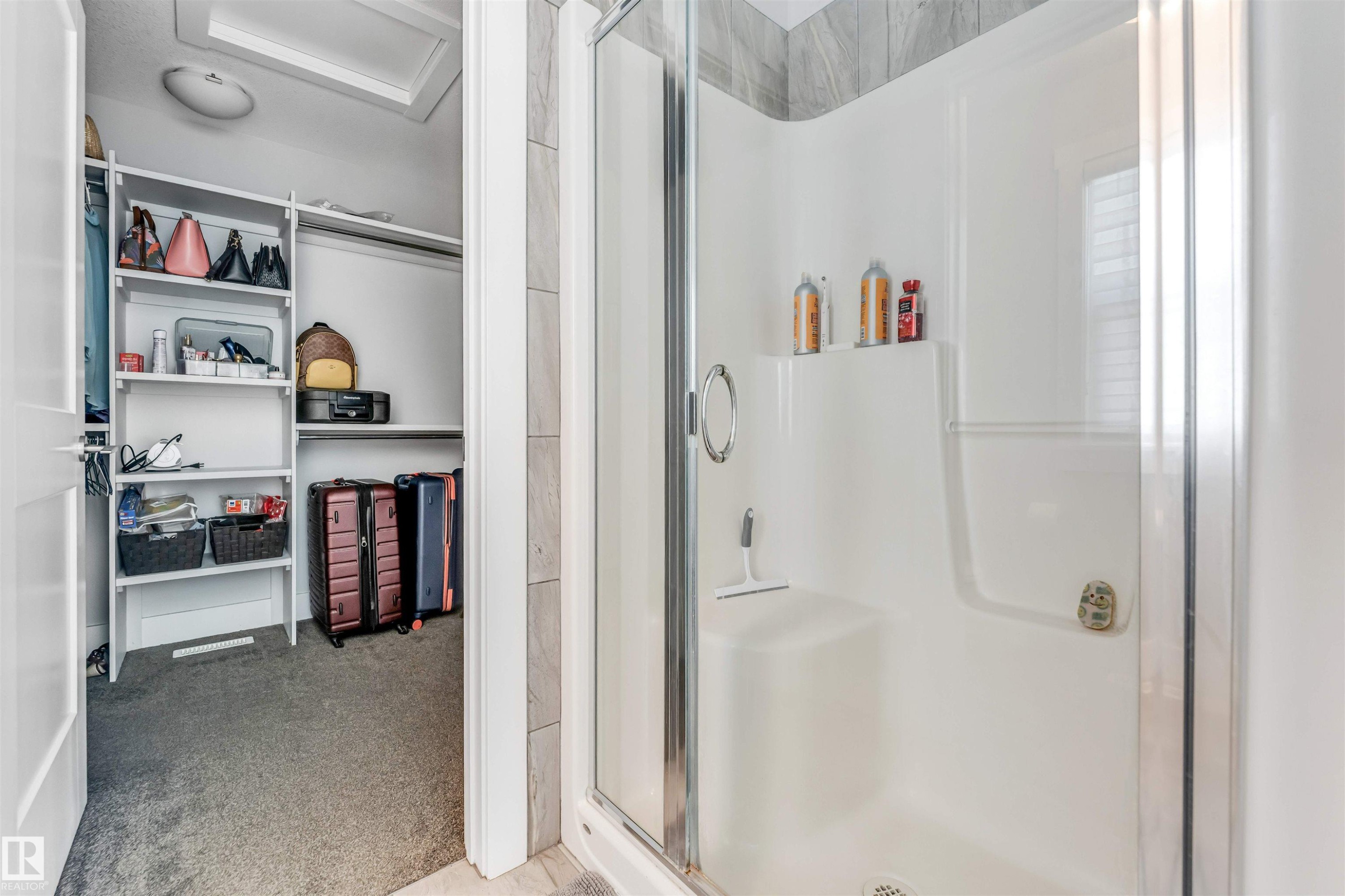 Shower enclosure with clear glass door, built-in seating, and integrated shelving - 8516 216 Street, Edmonton, AB
