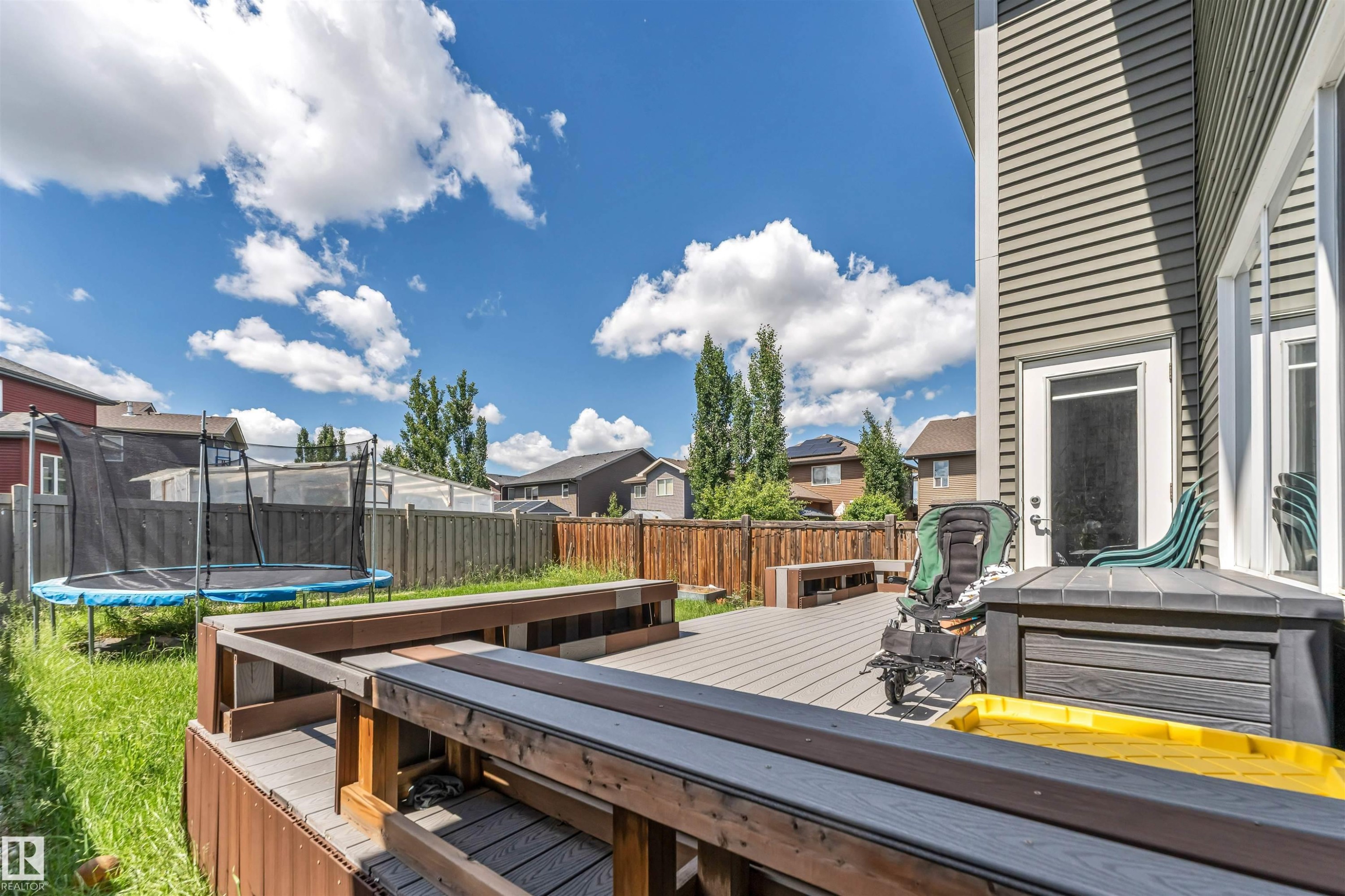 Spacious backyard featuring a multi-level composite deck with integrated bench seating, private wood fencing, and a manicured lawn area - 8516 216 Street, Edmonton, AB
