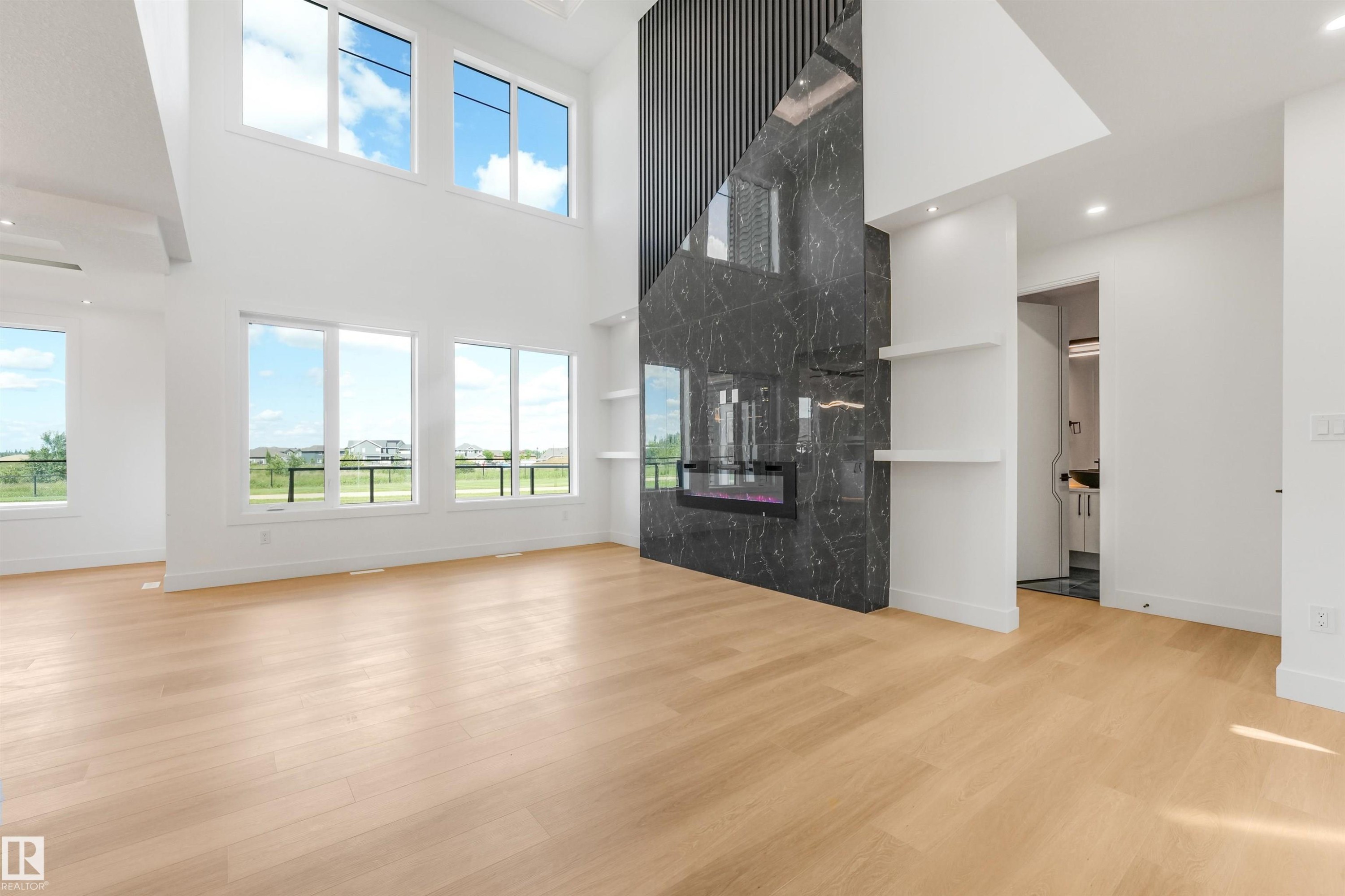 Great room featuring a full-height fireplace with black veined stone surround and an integrated linear electric firebox - 1180 Genesis Lake Boulevard, Stony Plain, AB
