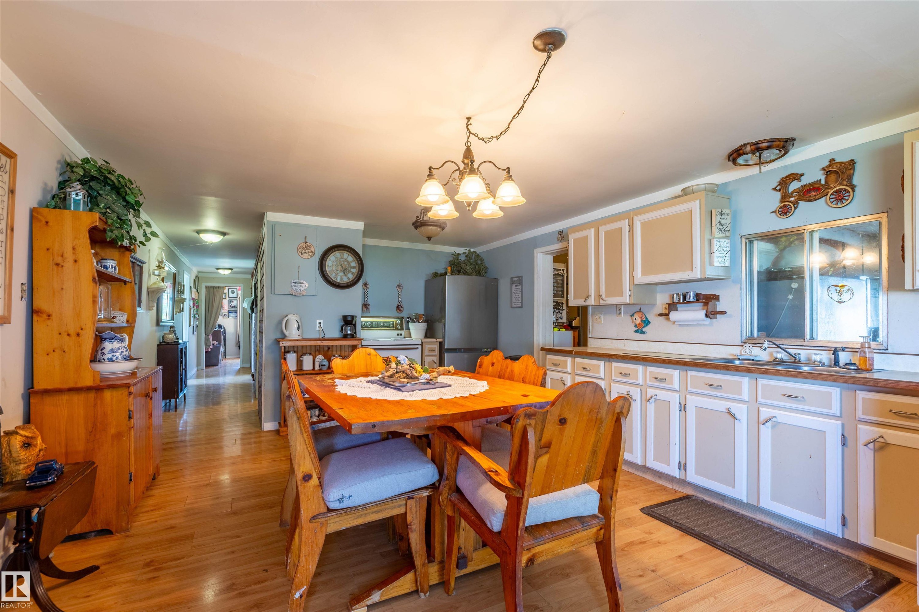 Open-concept kitchen and dining area featuring wood-finish flooring, white cabinetry with light brown panels, and wood countertops - 551027 Range Road 193, Rural Lamont County, AB
