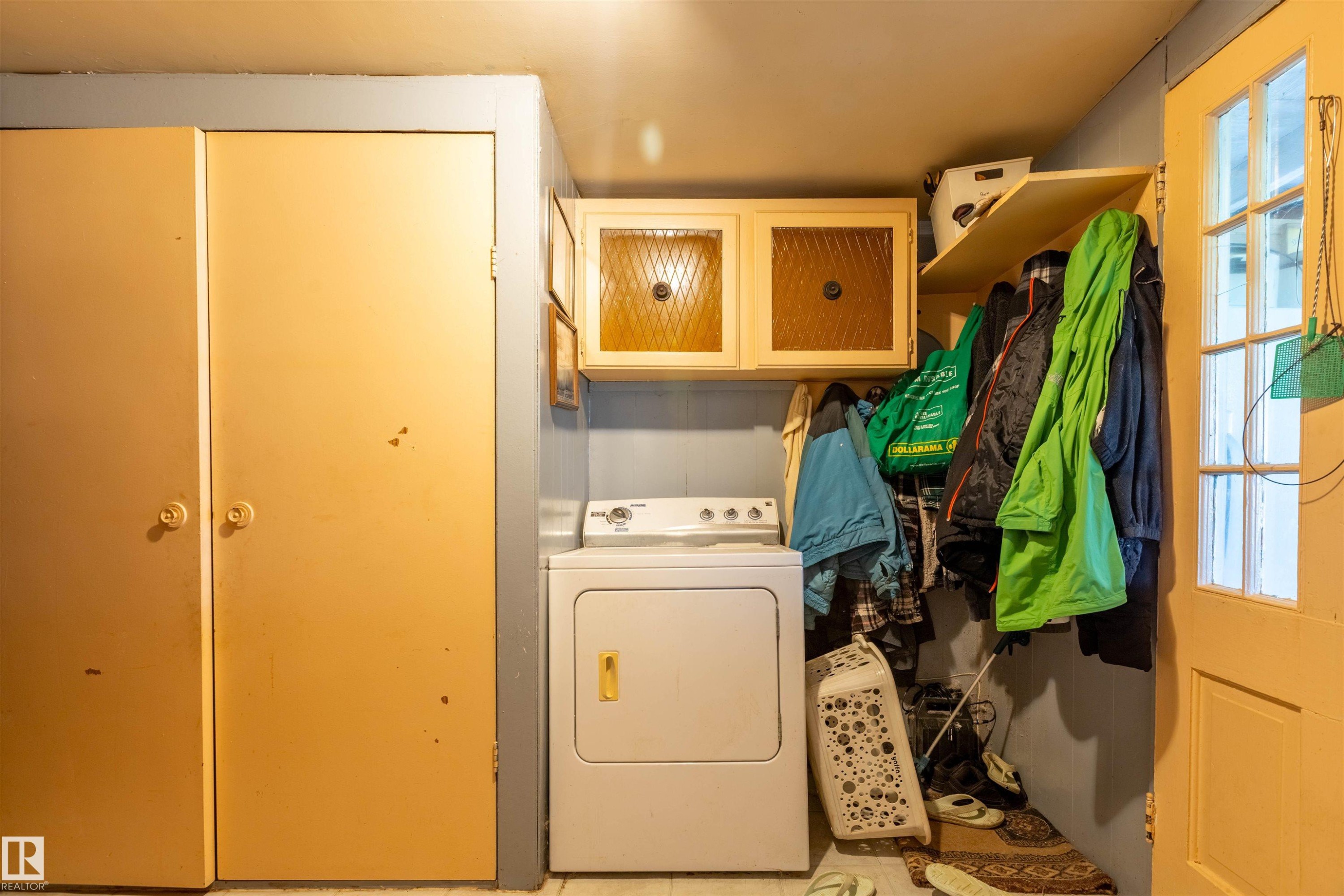 Utility area featuring a built-in shelf, two storage closets, and overhead cabinetry with frosted glass inserts - 551027 Range Road 193, Rural Lamont County, AB