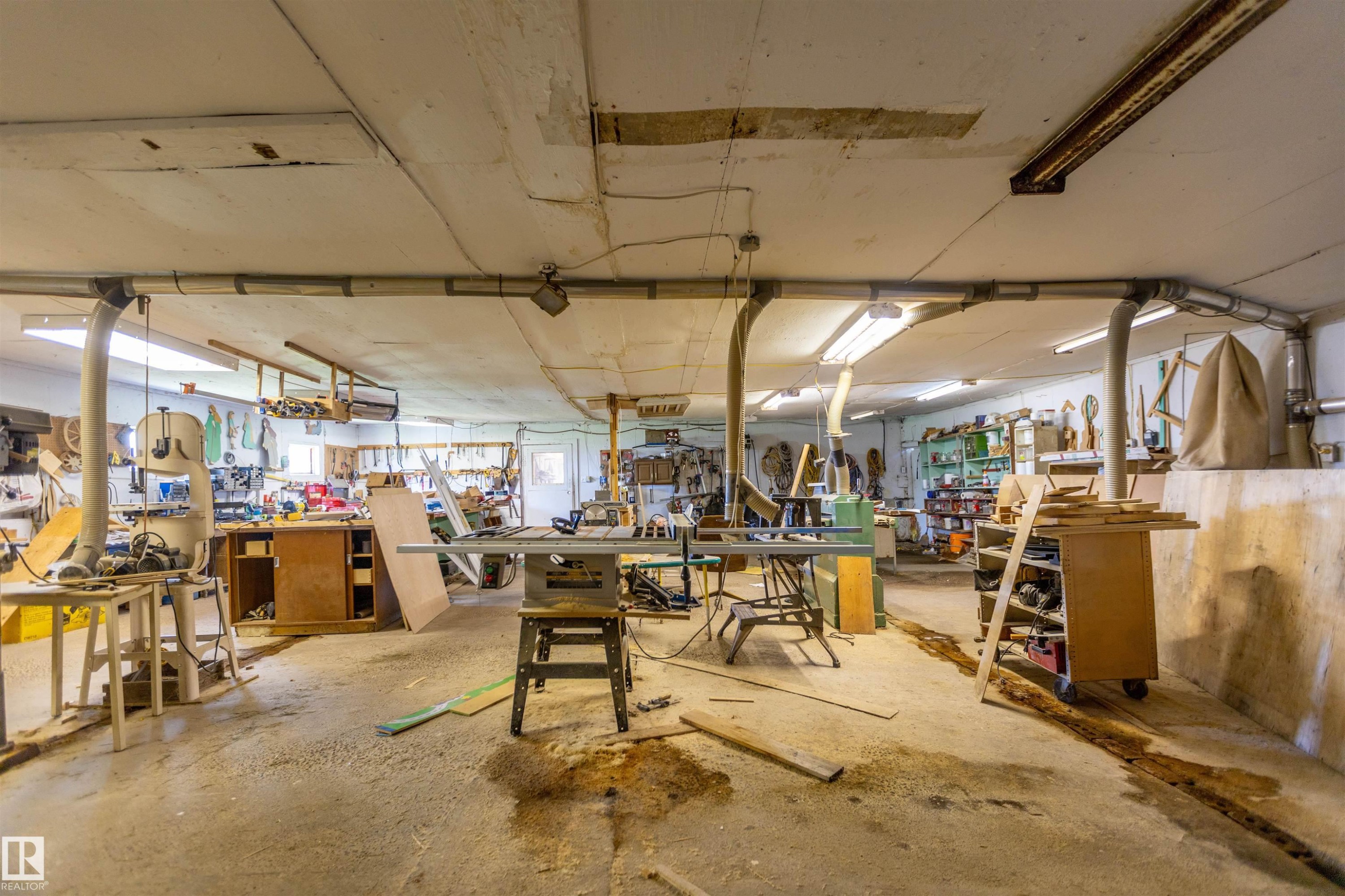 Spacious workshop area with concrete flooring, exposed overhead ductwork, and abundant fluorescent lighting - 551027 Range Road 193, Rural Lamont County, AB