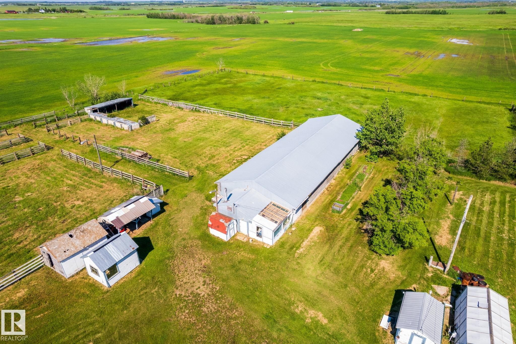 Expansive green acreage featuring a large agricultural building with a metal roof, multiple fenced enclosures, and several outbuildings - 551027 Range Road 193, Rural Lamont County, AB