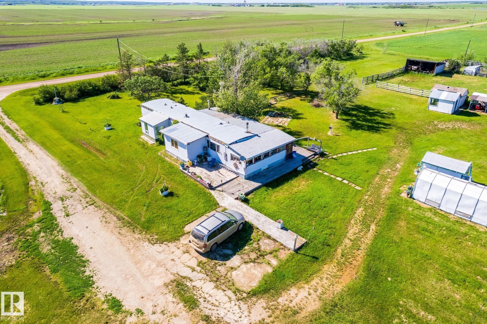Expansive property featuring a single-story residence with multiple outbuildings, including a large greenhouse and a fenced enclosure - 551027 Range Road 193, Rural Lamont County, AB