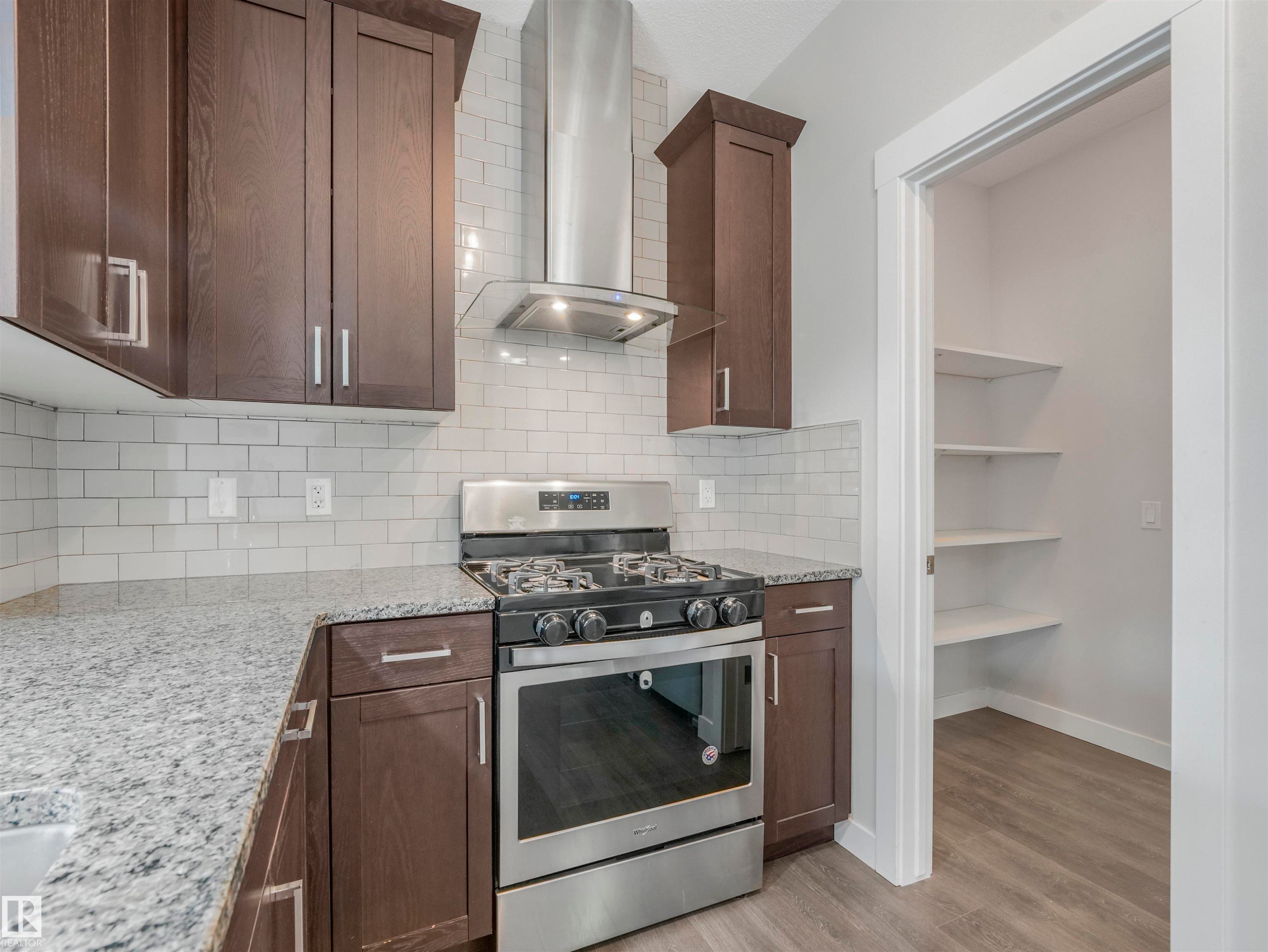 Modern kitchen featuring dark wood-finish cabinetry, light speckled countertops, and a subway tile backsplash - 20507 99 Avenue, Edmonton, AB - Indoor Photo Showing Kitchen