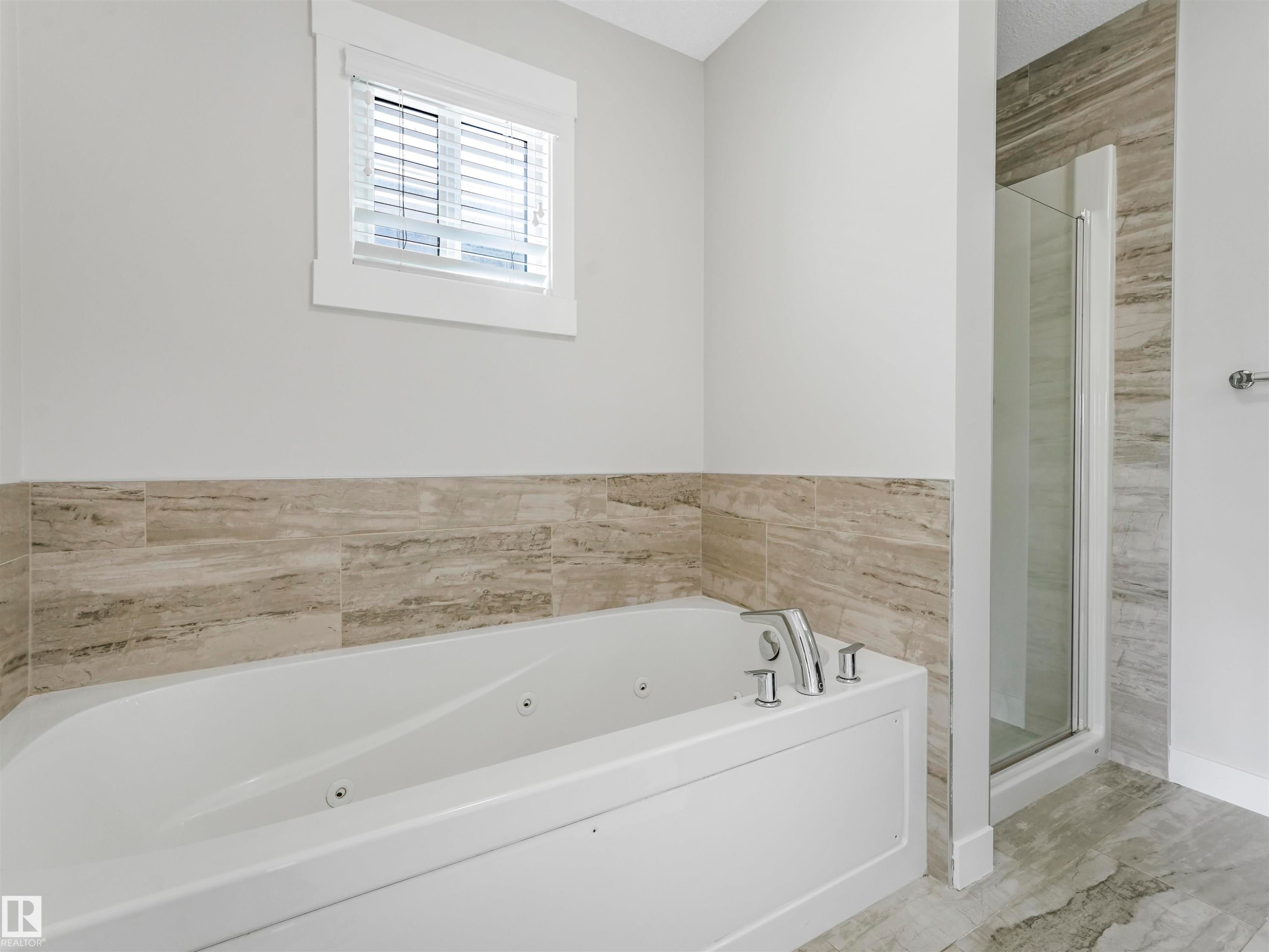 Soaking tub with integrated jets, chrome fixtures, and a tiled surround - 20507 99 Avenue, Edmonton, AB - Indoor Photo Showing Bathroom