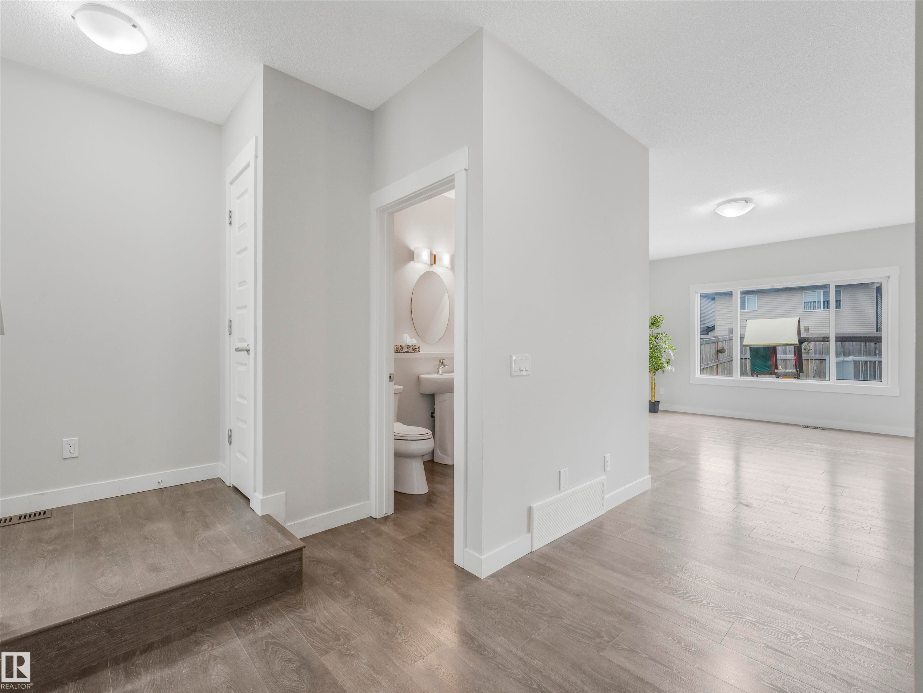 Open-concept living space with wood-finish flooring, recessed lighting, and a prominent window - 20507 99 Avenue, Edmonton, AB - Indoor Photo Showing Other Room
