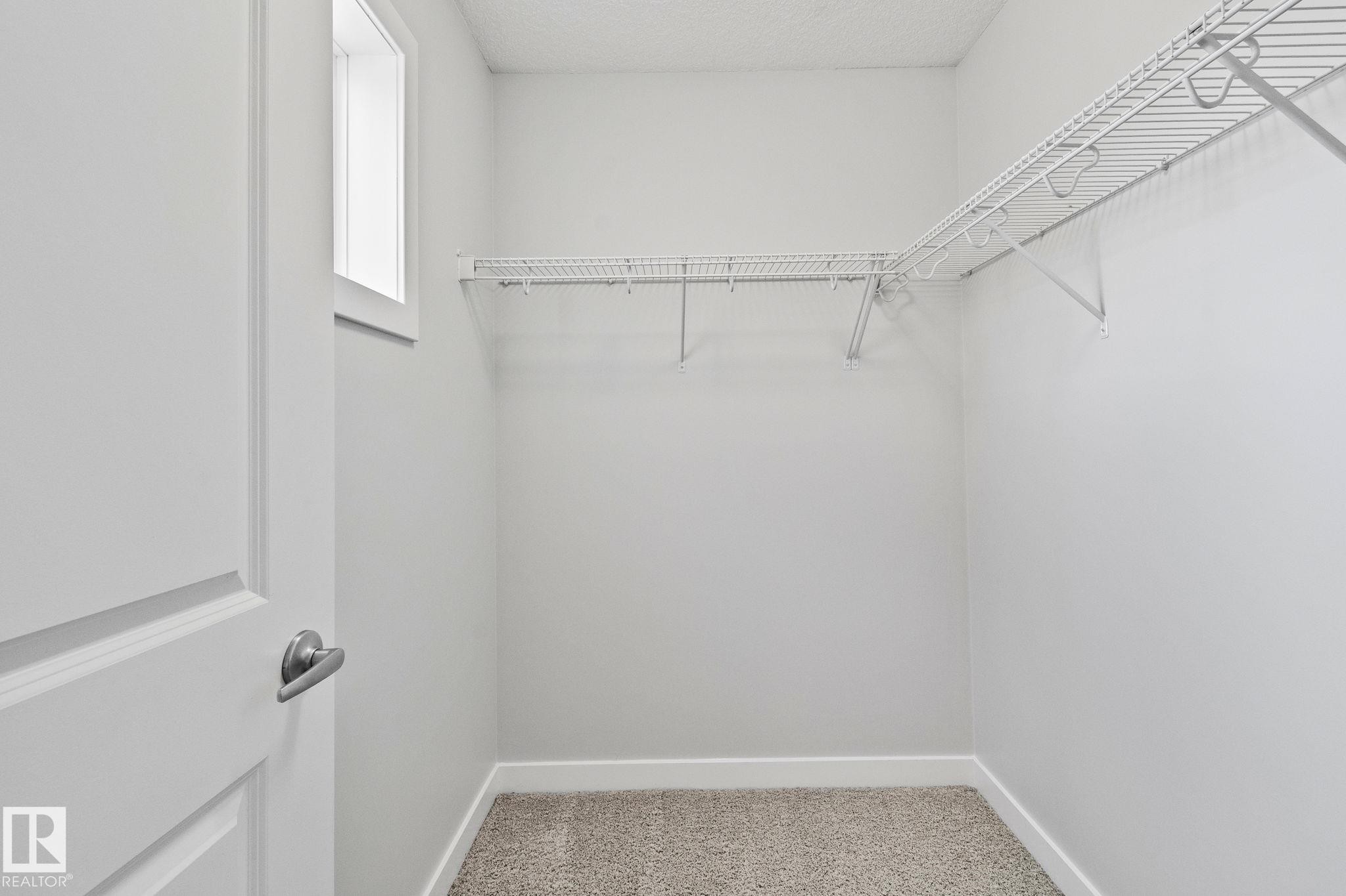 Walk-in closet with wire shelving system, light neutral walls, and window for natural light - 614 Mcdonough Link, Edmonton, AB