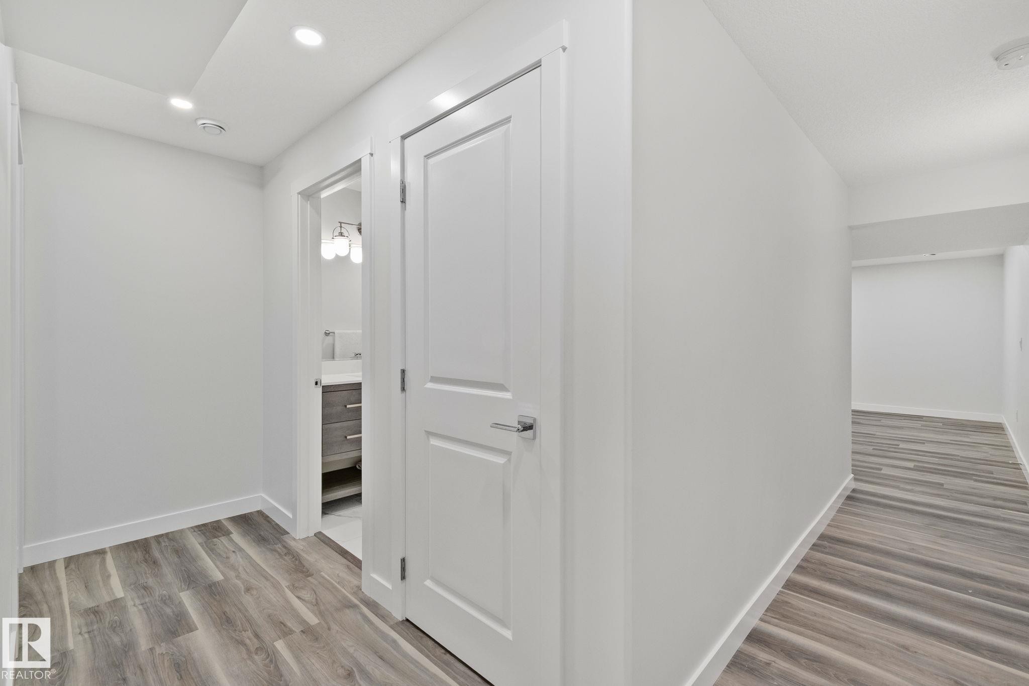 Hallway with wood-finish flooring, recessed lighting, and white baseboards - 614 Mcdonough Link, Edmonton, AB
