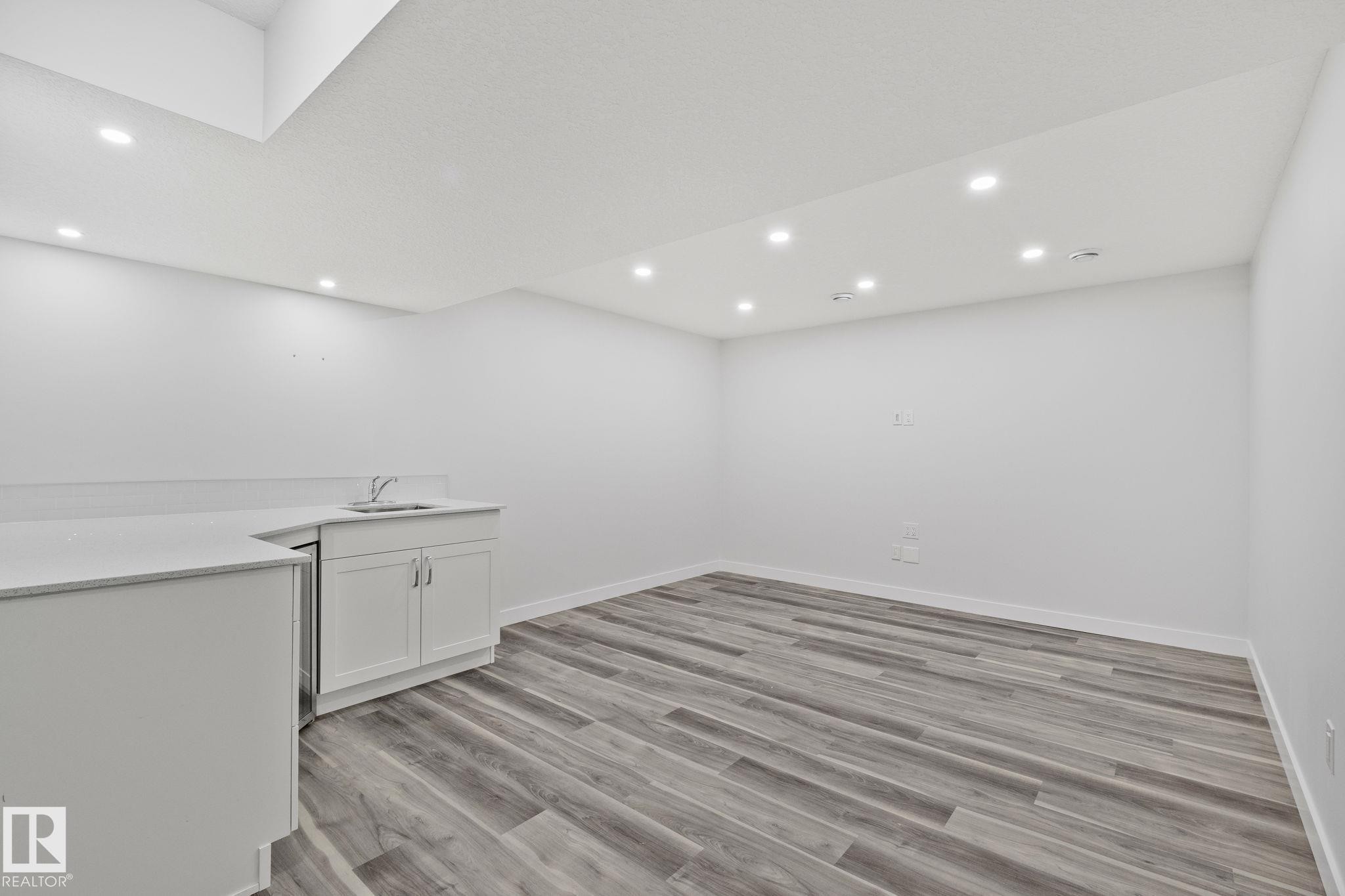Wet bar featuring a built-in sink, white cabinetry, and a light-toned countertop - 614 Mcdonough Link, Edmonton, AB