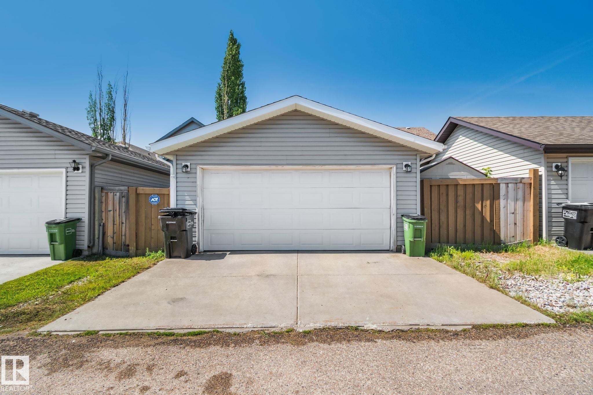 Two-car garage with light gray siding, white garage door, and concrete driveway - 614 Mcdonough Link, Edmonton, AB