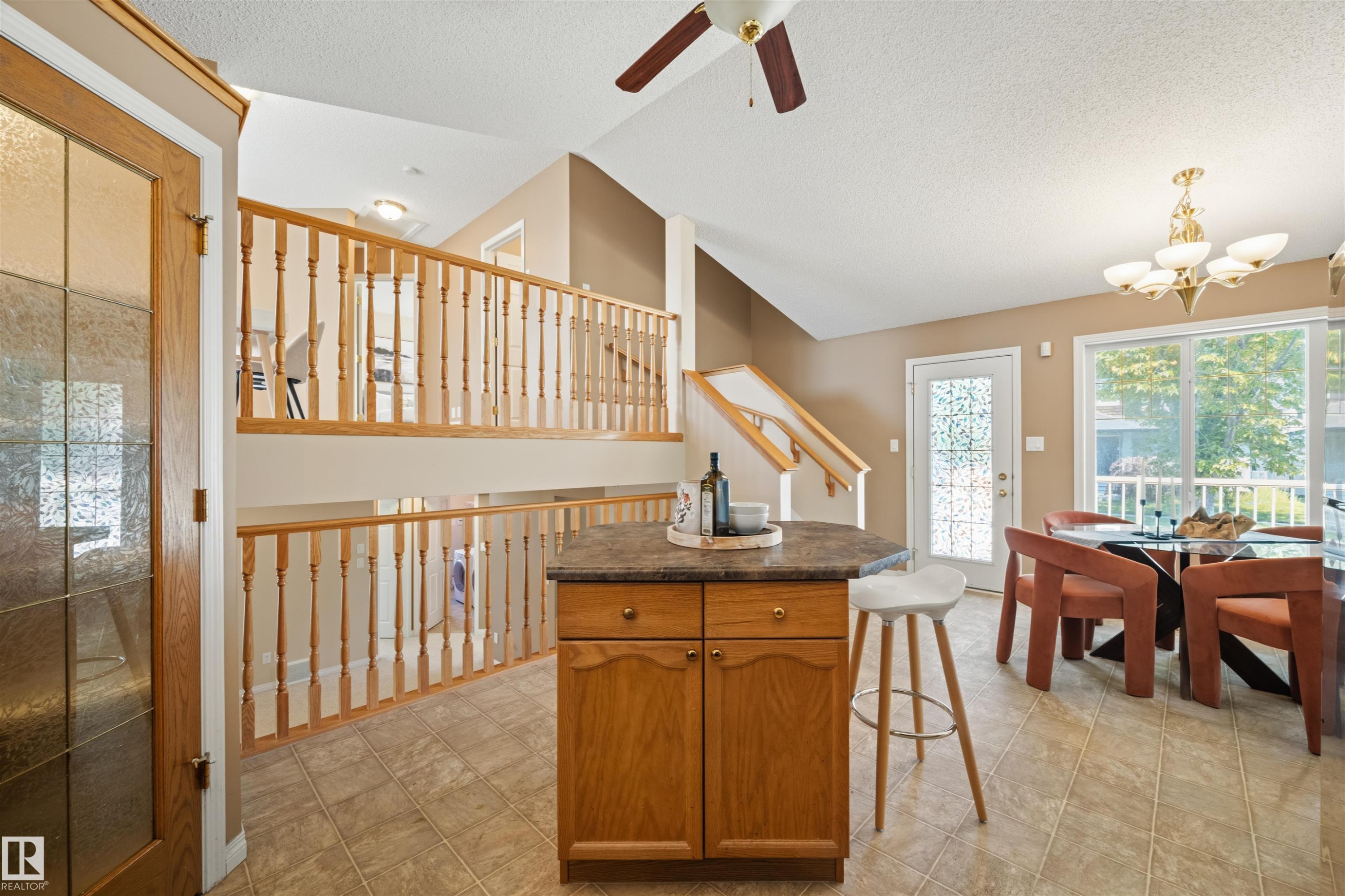 Open-concept living space featuring a central wood-finish island with a dark countertop - 7838 Schmid Place Nw, Edmonton, AB - Indoor