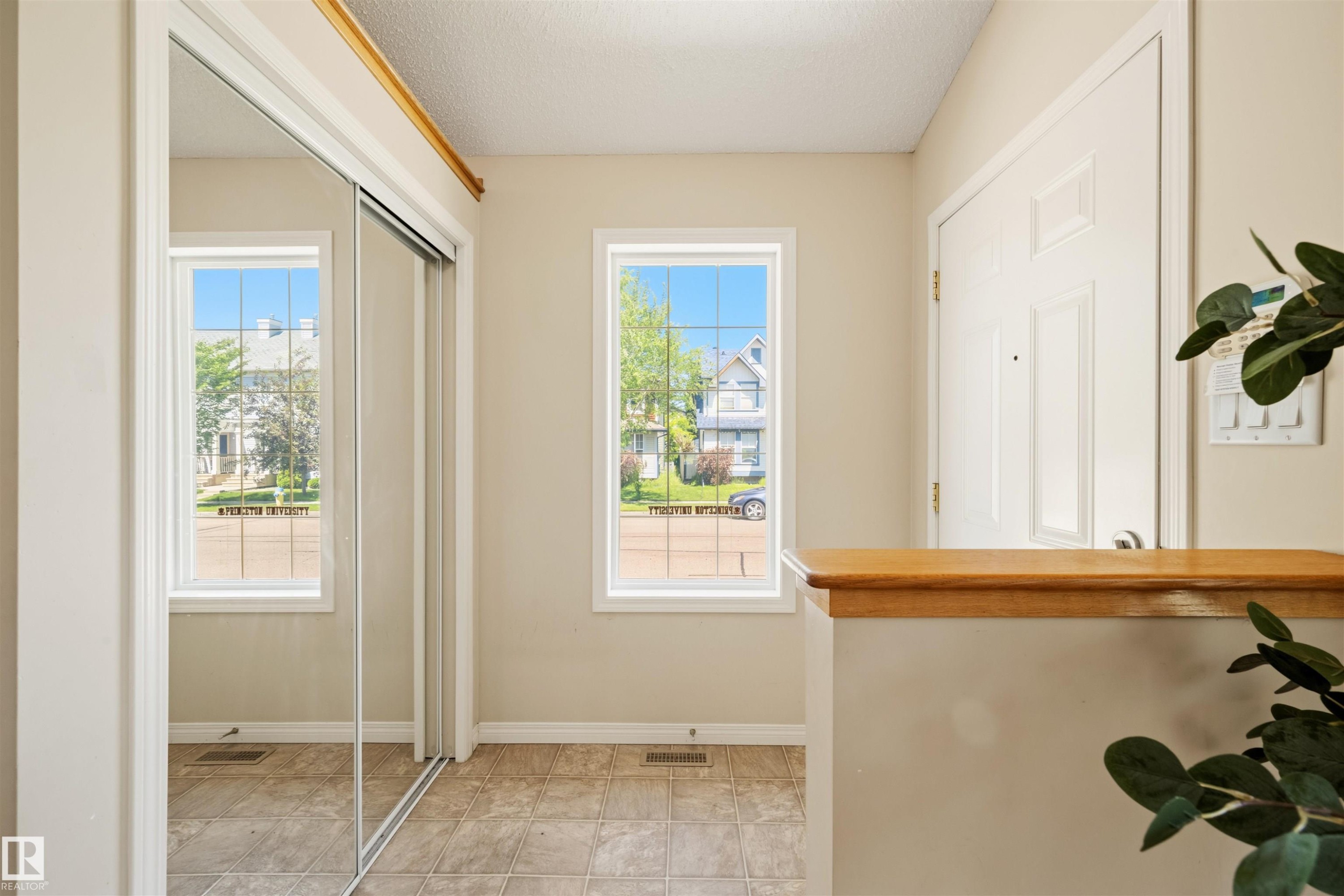 Entryway featuring two windows, mirrored sliding closet doors, a paneled entry door, and tiled flooring - 7838 Schmid Place Nw, Edmonton, AB - Indoor Photo Showing Other Room