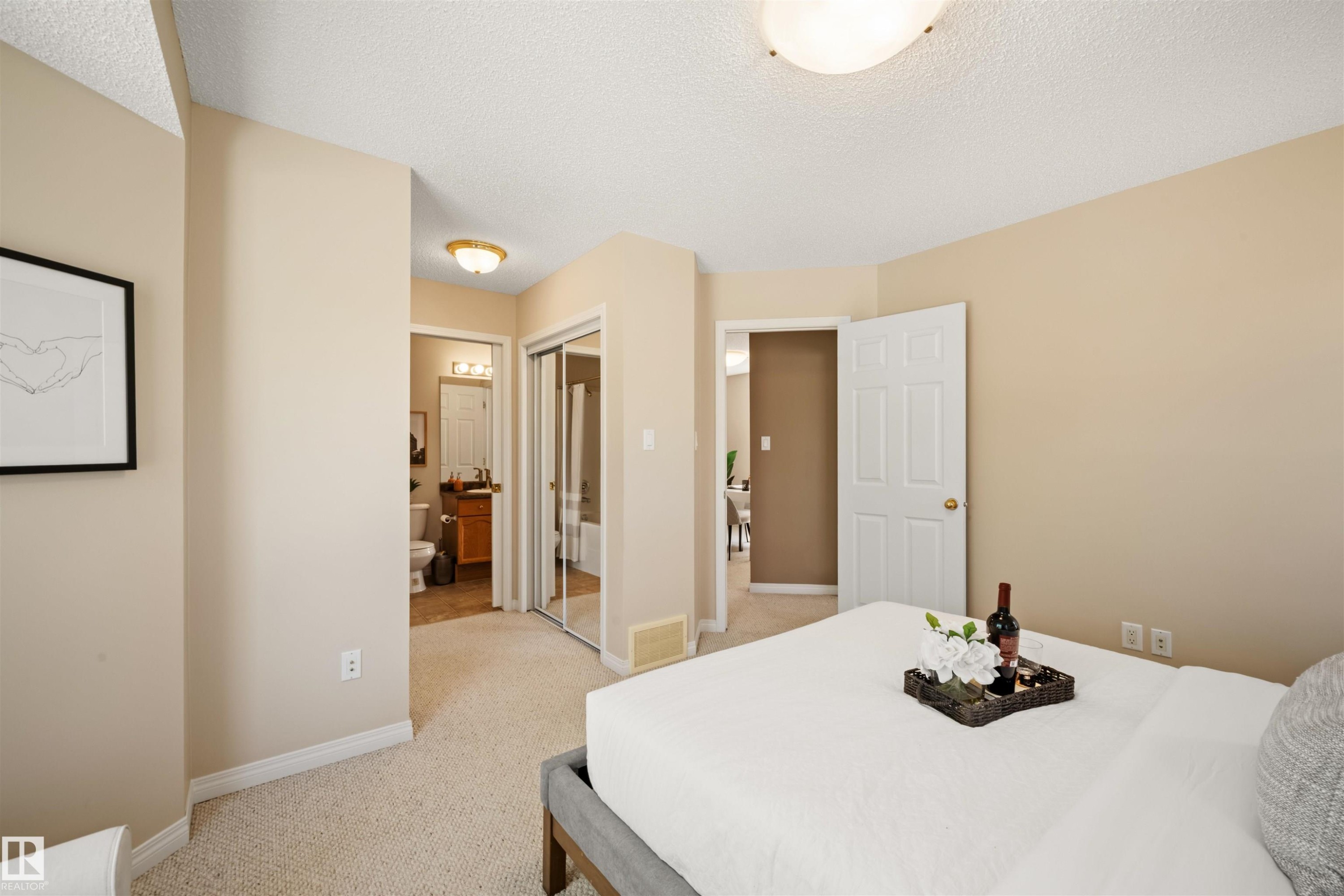 Neutral tone walls with white trim, soft carpeting, and a built-in closet with mirrored sliding doors - 7838 Schmid Place Nw, Edmonton, AB - Indoor Photo Showing Bedroom
