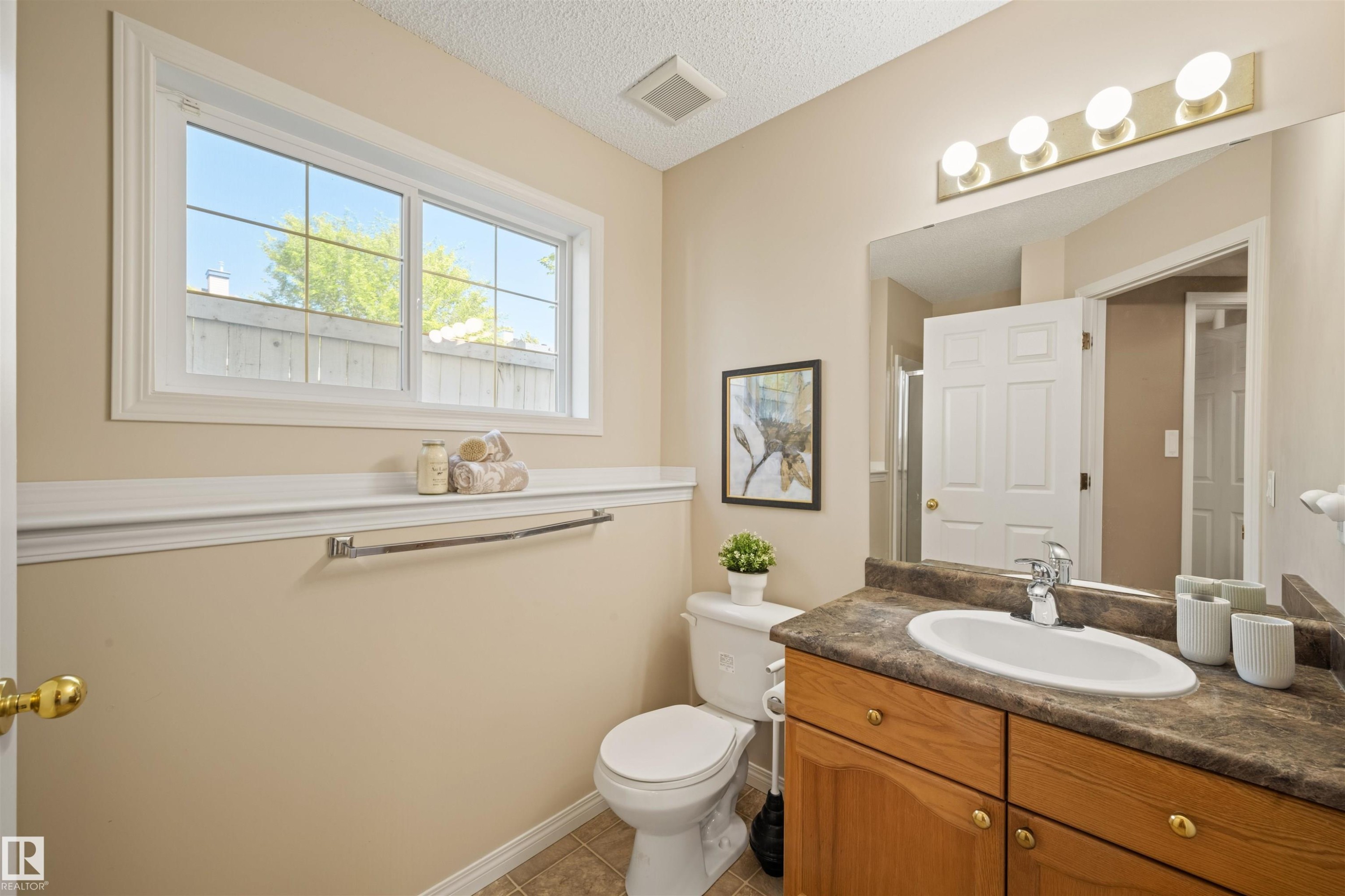 Bathroom featuring a wood-finish vanity with an integrated sink and a neutral countertop - 7838 Schmid Place Nw, Edmonton, AB - Indoor Photo Showing Bathroom