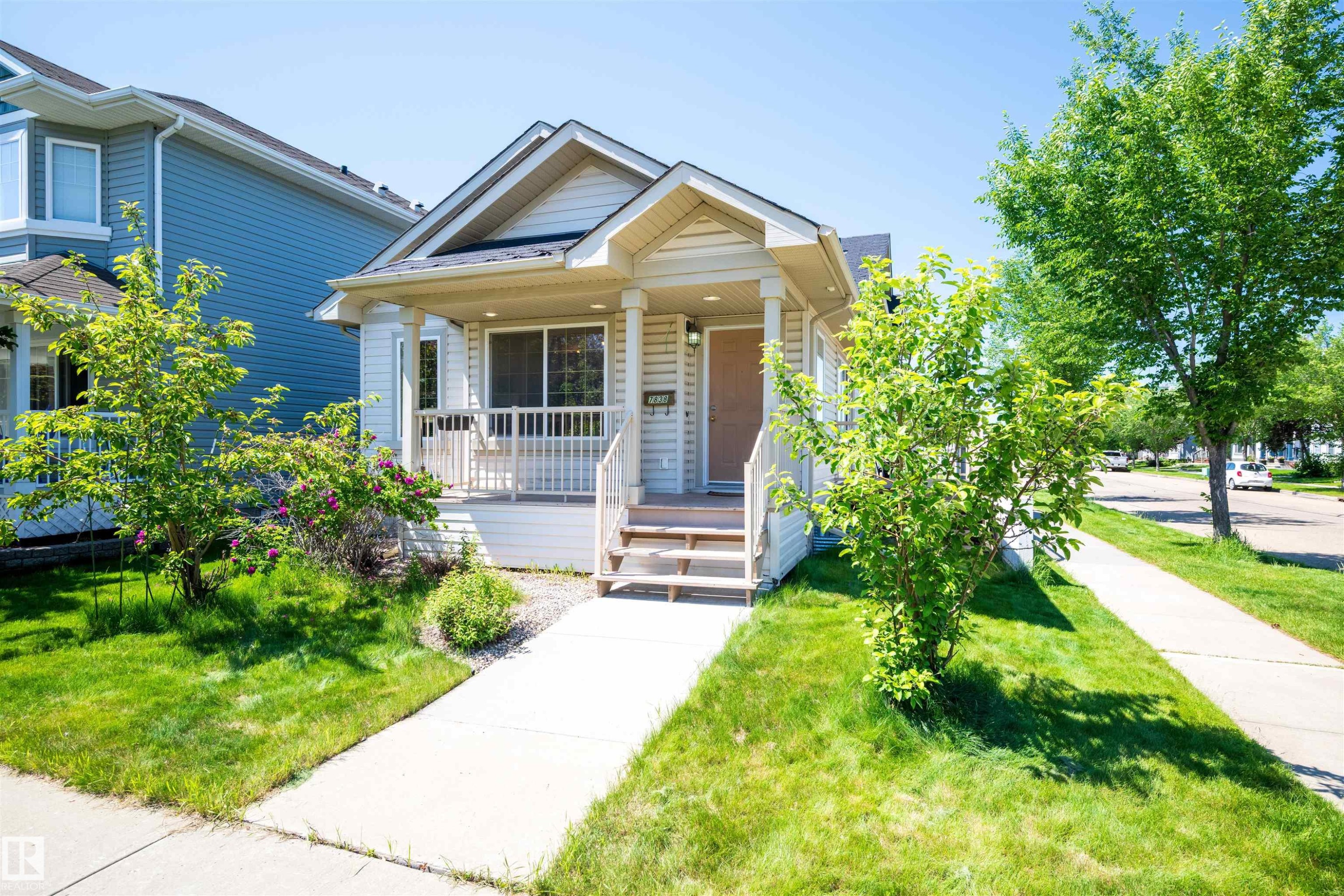 Charming single-story residence featuring light-colored siding and a covered front porch with white railings - 7838 Schmid Place Nw, Edmonton, AB - Outdoor With Facade