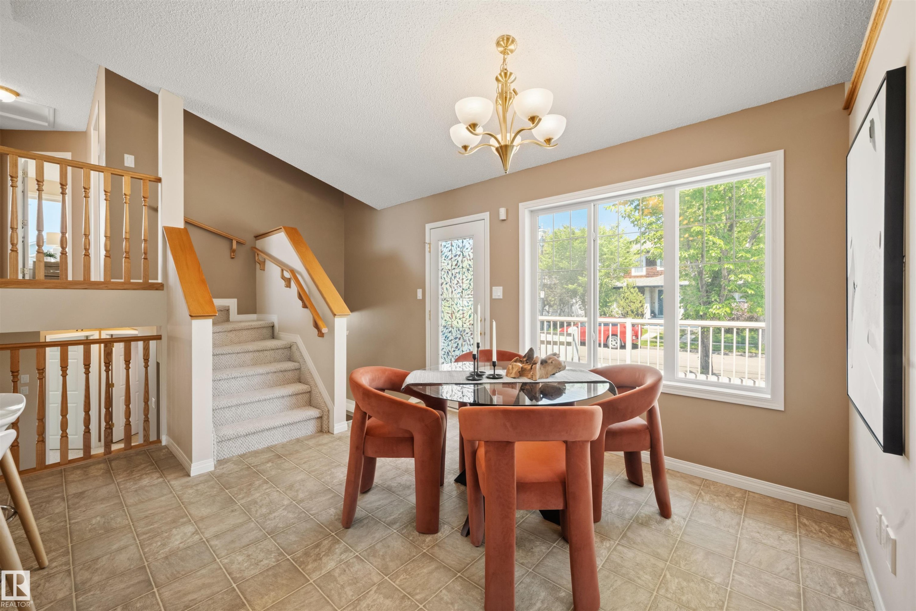 Neutral tile flooring extending to a multi-level staircase with carpeted treads and wood handrails - 7838 Schmid Place Nw, Edmonton, AB - Indoor Photo Showing Dining Room