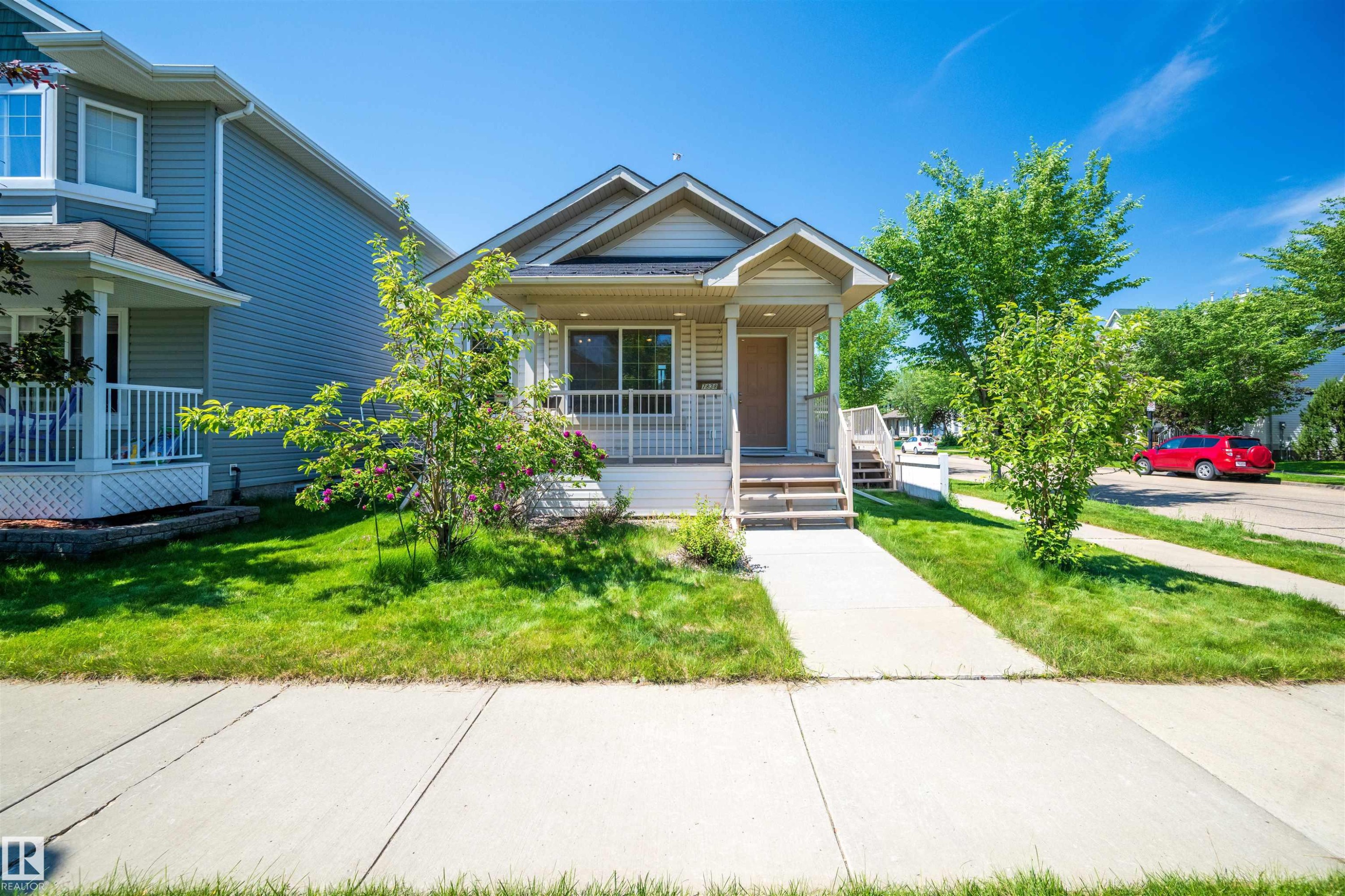 Warm toned siding exterior with a covered front porch and white railing - 7838 Schmid Place Nw, Edmonton, AB - Outdoor With Facade