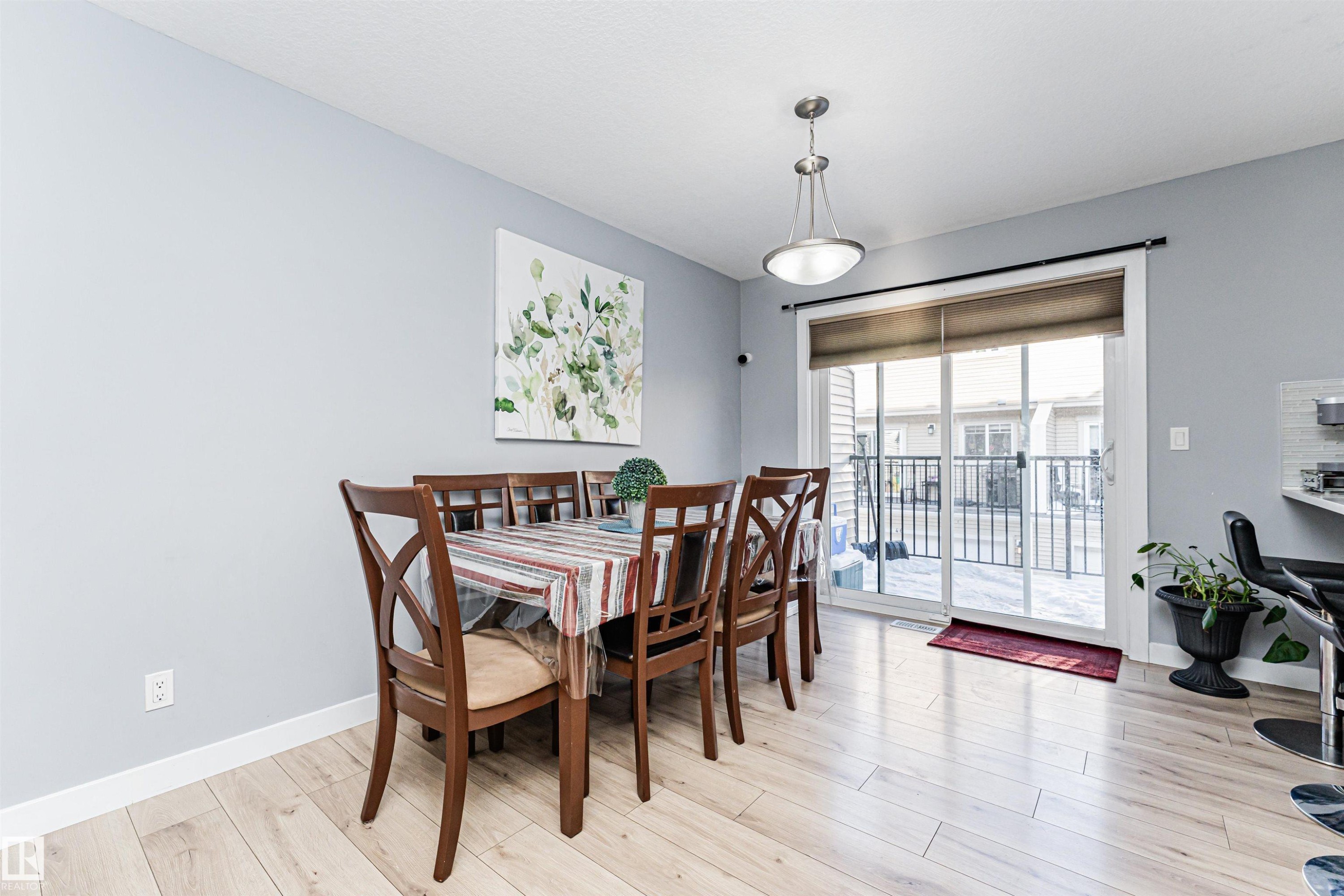 Dining area featuring light wood-finish flooring, light gray walls, and a contemporary pendant light fixture - 35 675 Albany Way, Edmonton, AB
