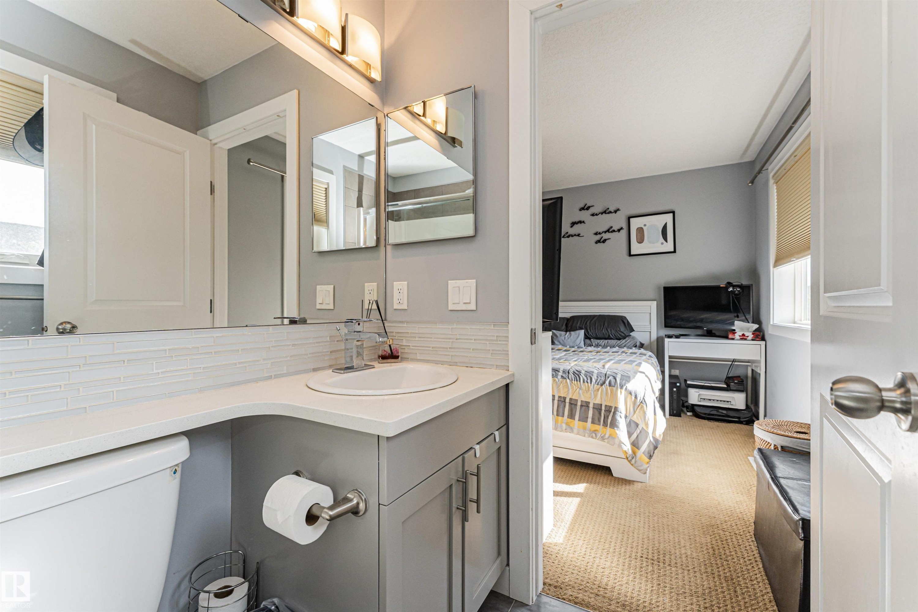 Bathroom vanity featuring a vessel sink, single-handle faucet, and light gray cabinetry - 35 675 Albany Way, Edmonton, AB