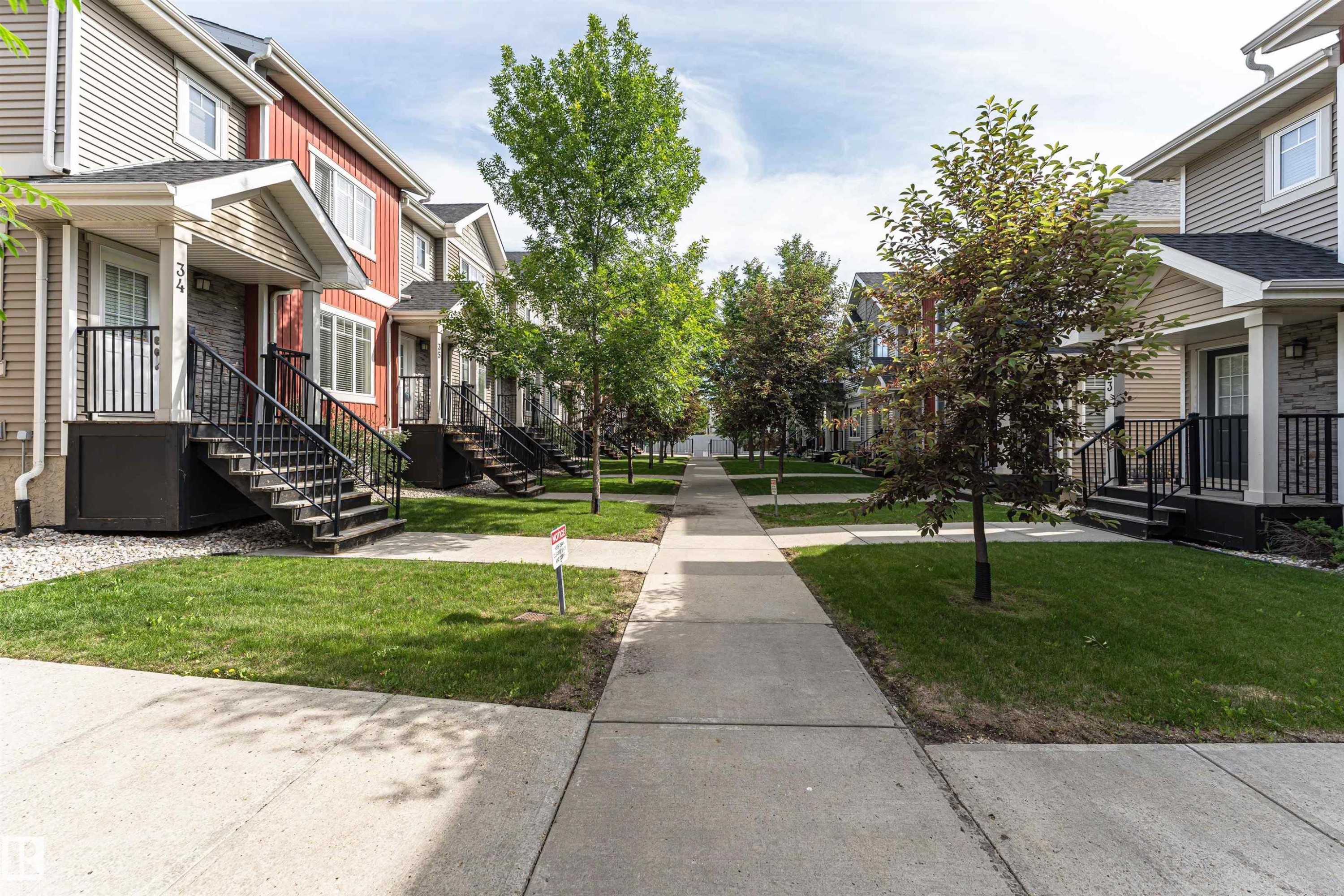 Pedestrian-friendly concrete walkway bordered by manicured lawns and mature trees - 35 675 Albany Way, Edmonton, AB
