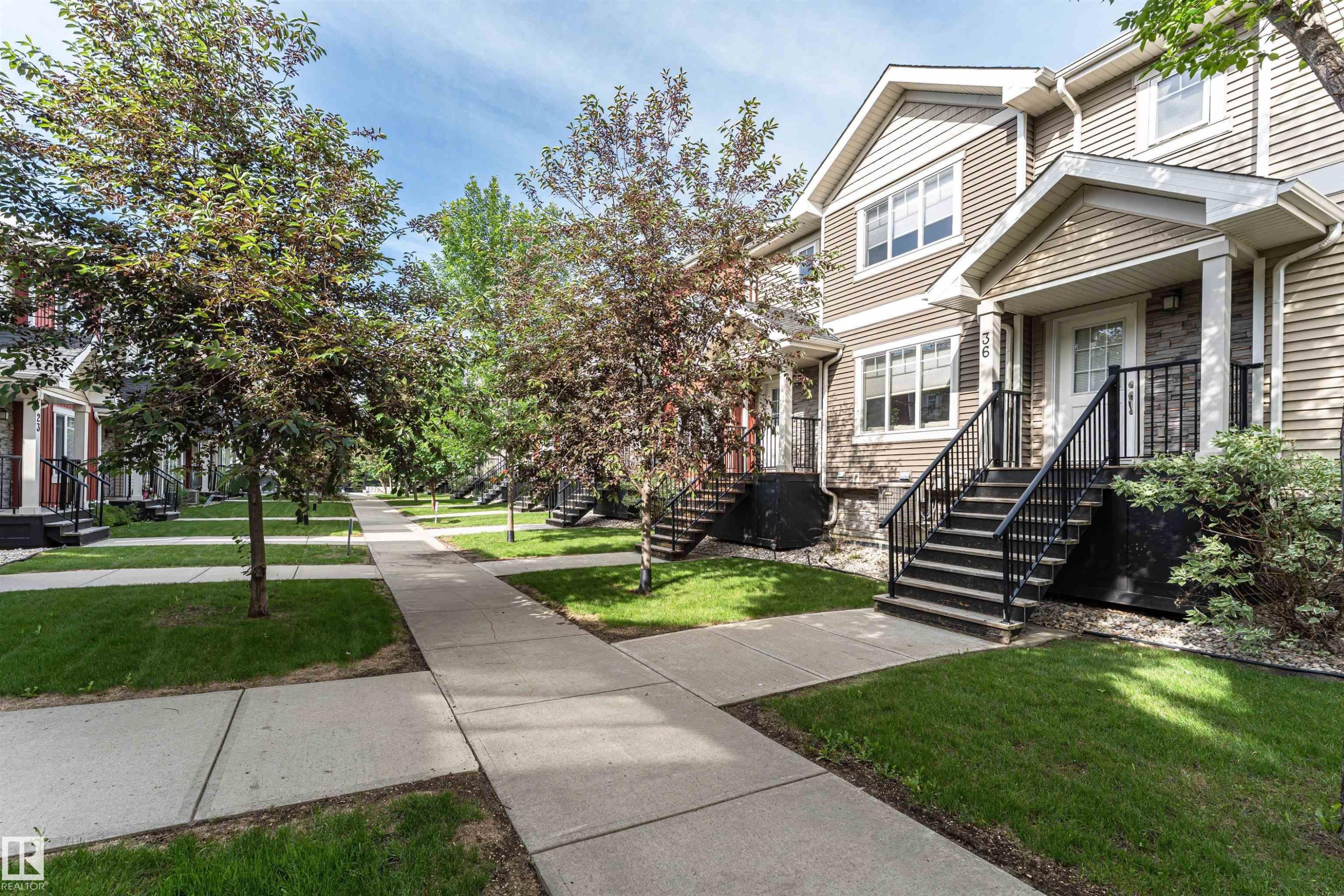 Townhome exterior featuring horizontal siding and stone accents - 35 675 Albany Way, Edmonton, AB
