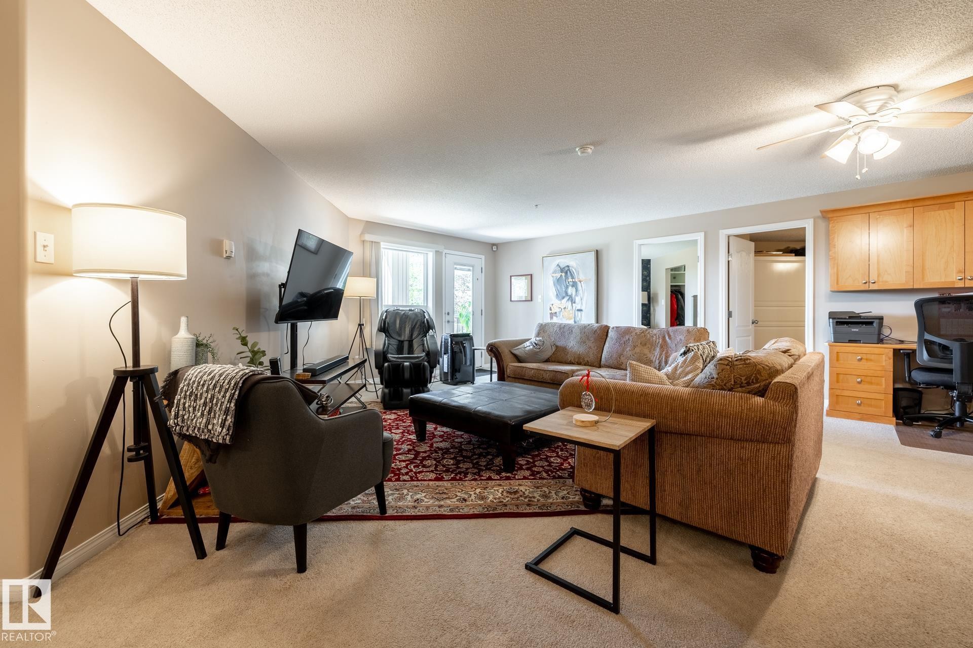 Carpeted living area featuring a ceiling fan, recessed lighting, and a built-in desk with overhead cabinetry - 330 1520 Hammond Gate Gate, Edmonton, AB