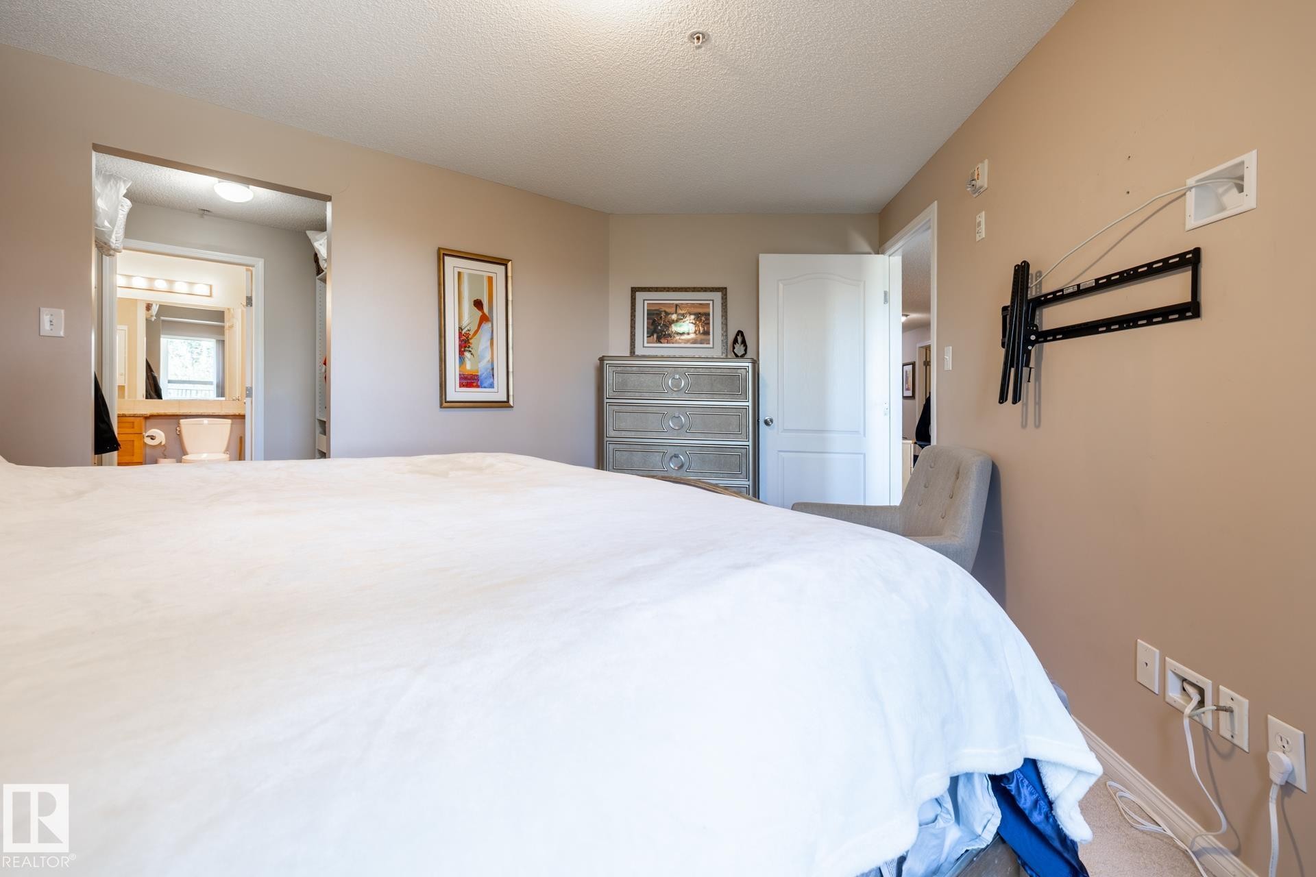 Bedroom featuring a neutral color palette, ceiling-mounted lighting, and a wall-mounted bracket for media - 330 1520 Hammond Gate Gate, Edmonton, AB