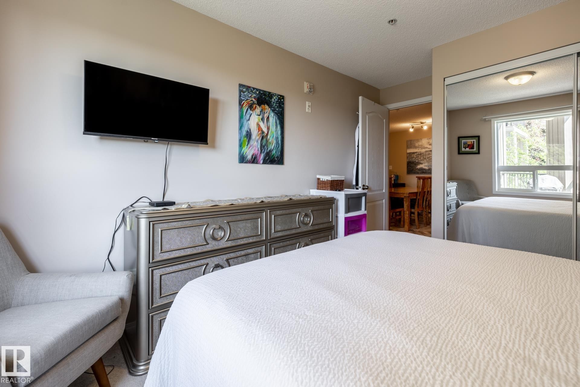 Bedroom featuring warm neutral wall tones and a built-in mirrored closet - 330 1520 Hammond Gate Gate, Edmonton, AB