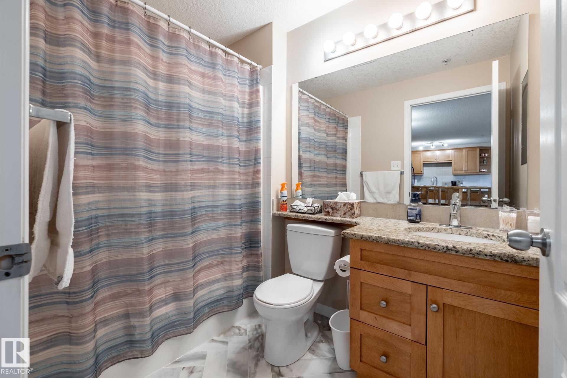 Bathroom featuring a single vanity with wood cabinetry, a granite-finish countertop, and an undermount sink - 330 1520 Hammond Gate Gate, Edmonton, AB