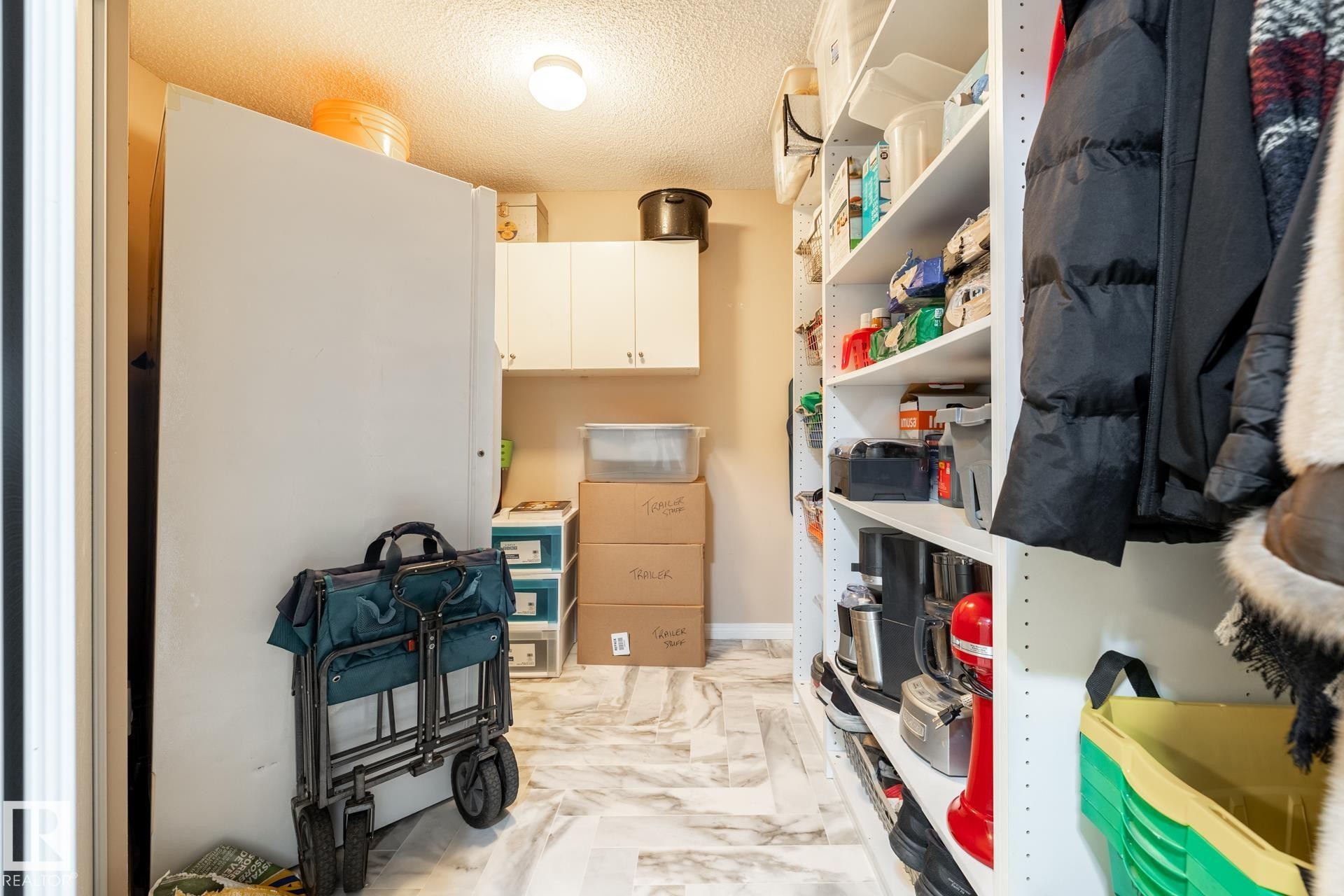 Spacious utility area featuring light wood-finish flooring, white overhead cabinetry, and extensive built-in shelving - 330 1520 Hammond Gate Gate, Edmonton, AB