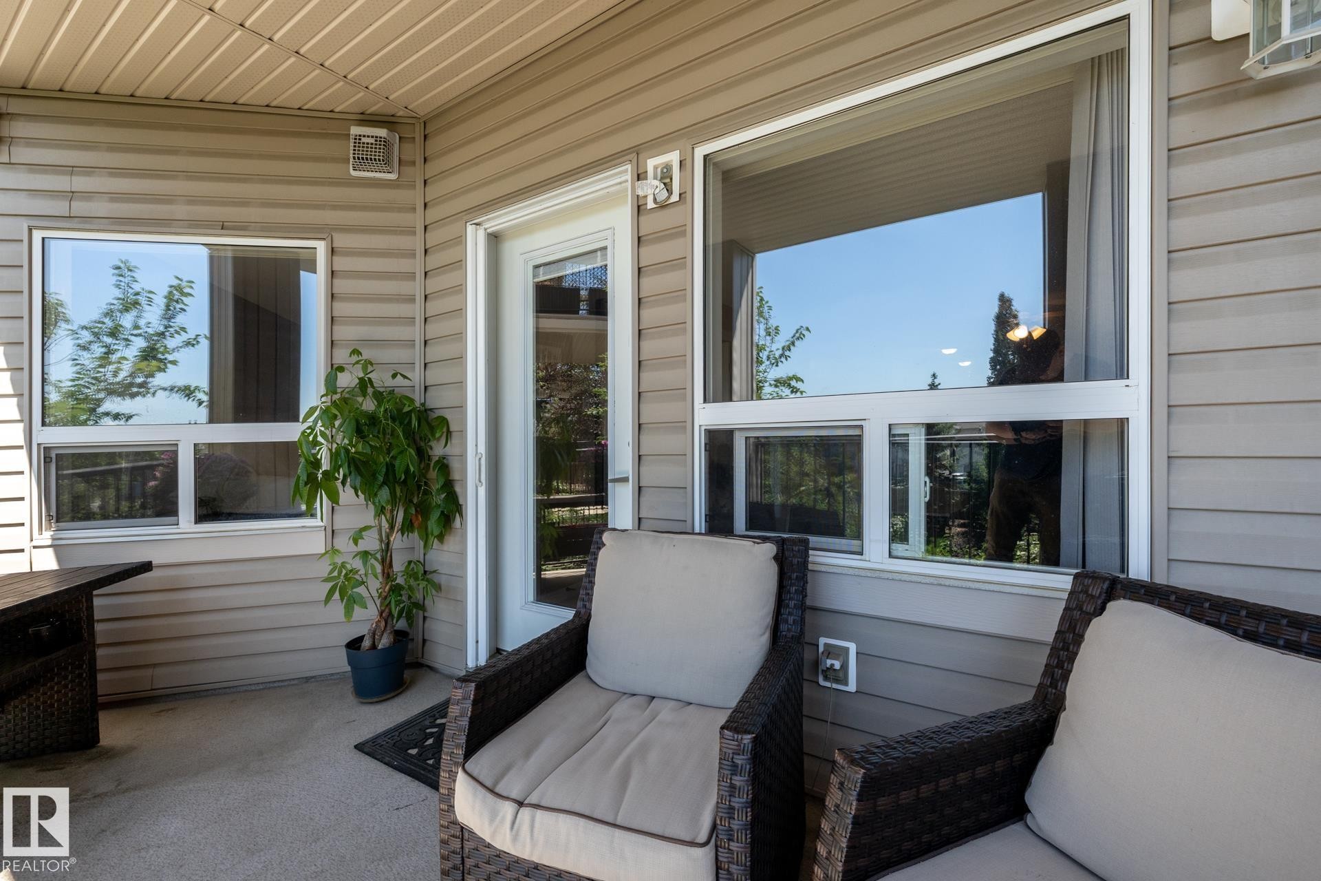 Patio area featuring light-toned vinyl siding and a textured concrete surface - 330 1520 Hammond Gate Gate, Edmonton, AB