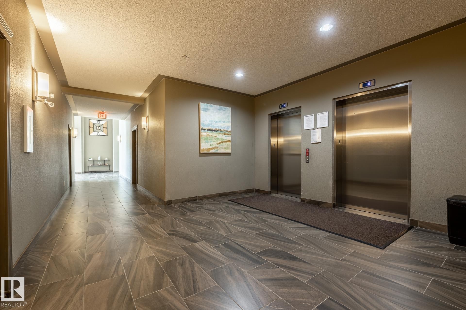 Elevator lobby featuring two stainless steel elevators, overhead recessed lighting, and wall-mounted sconces - 330 1520 Hammond Gate Gate, Edmonton, AB