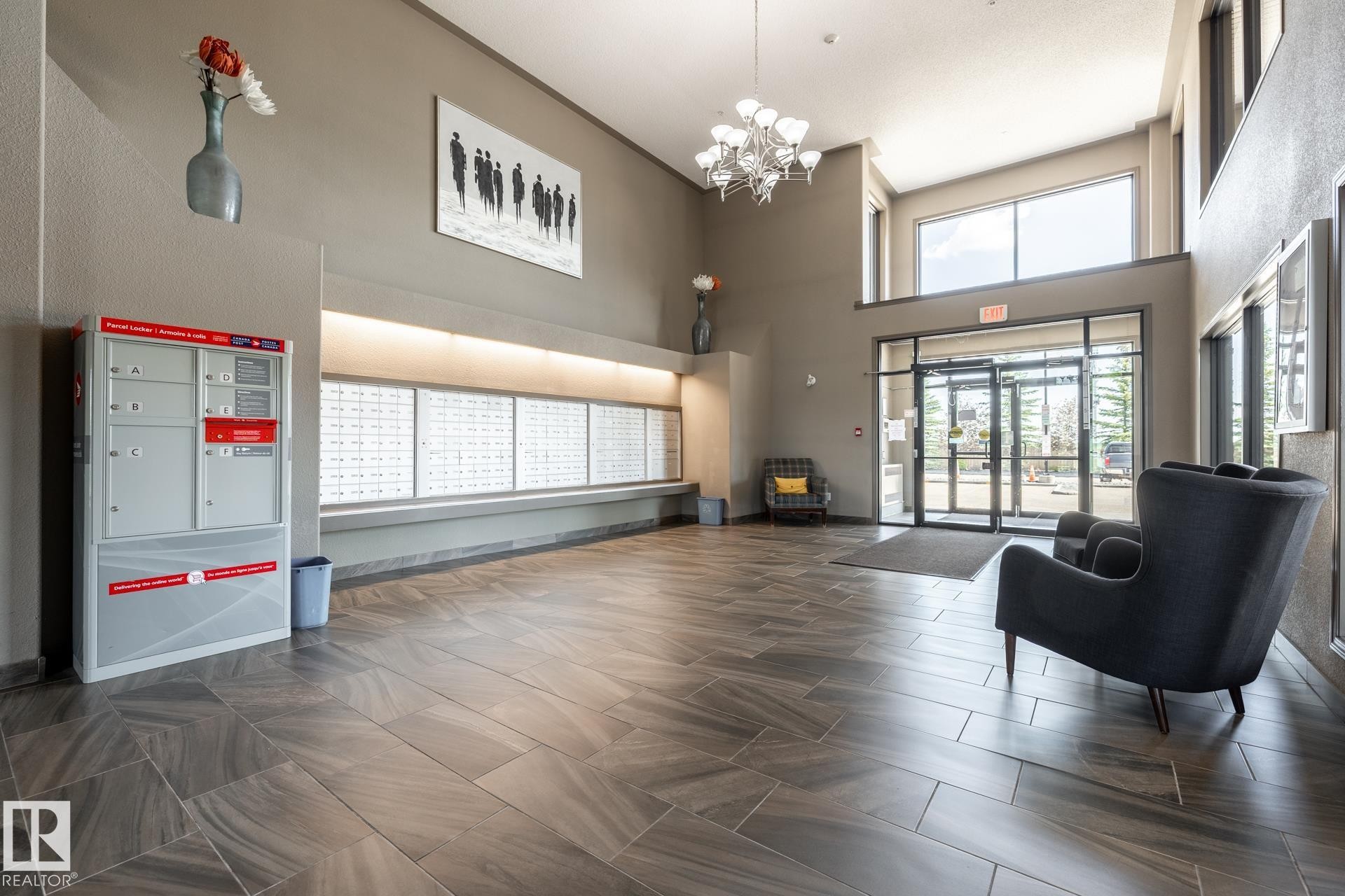 Spacious lobby featuring large format tile flooring, a two-story ceiling, and a prominent wall of individual mailboxes - 330 1520 Hammond Gate Gate, Edmonton, AB