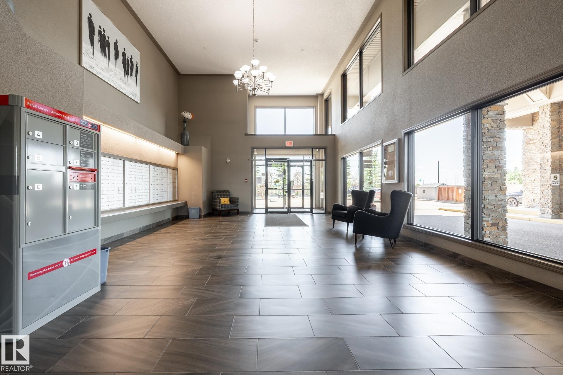 Spacious lobby featuring wood-finish tile flooring, large floor-to-ceiling windows, and recessed lighting - 330 1520 Hammond Gate Gate, Edmonton, AB